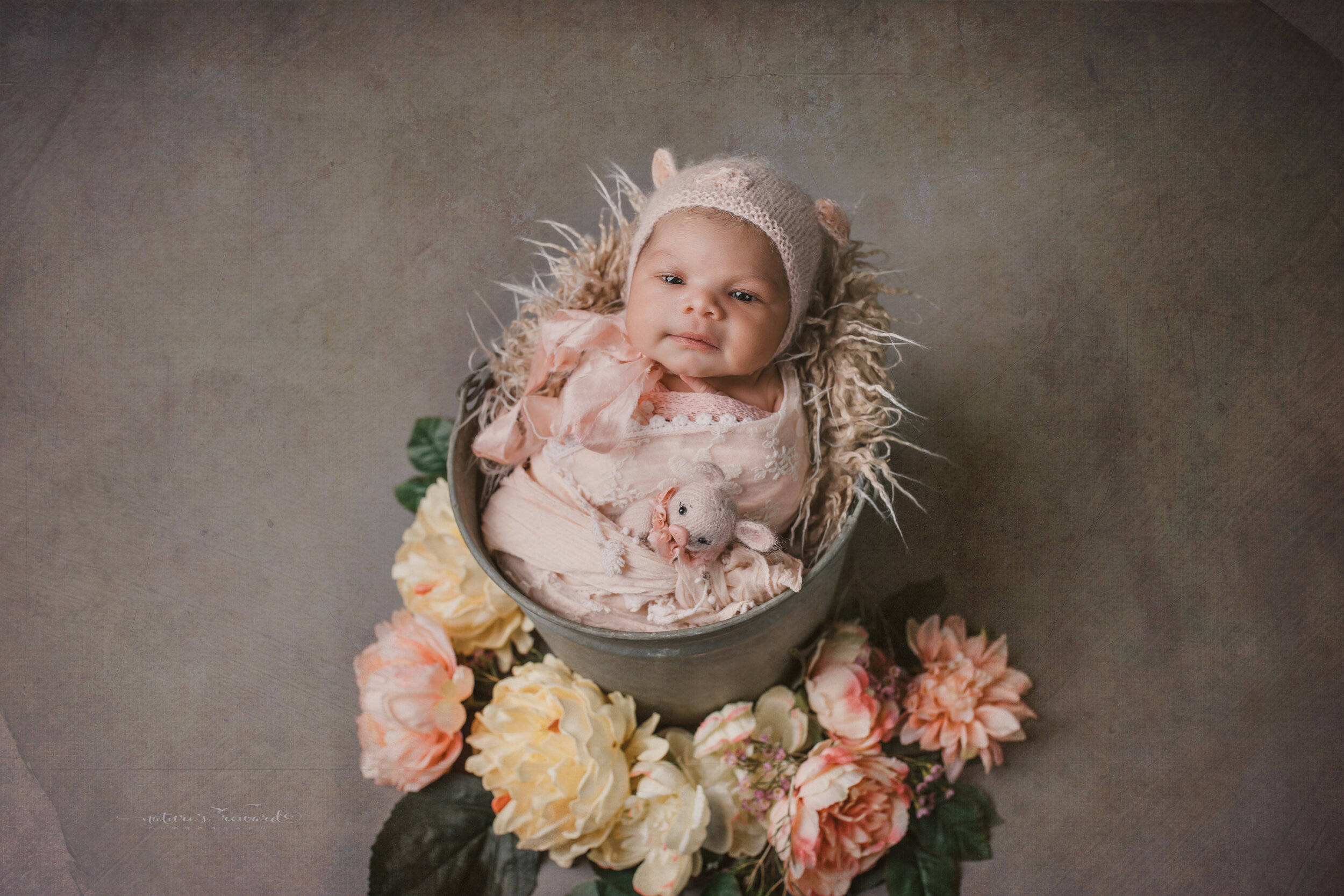 Newborn Baby girl swaddled in natural neutrals in the year of the pig bonnet and in a bucket a portrait by Nature’s Reward Photography
