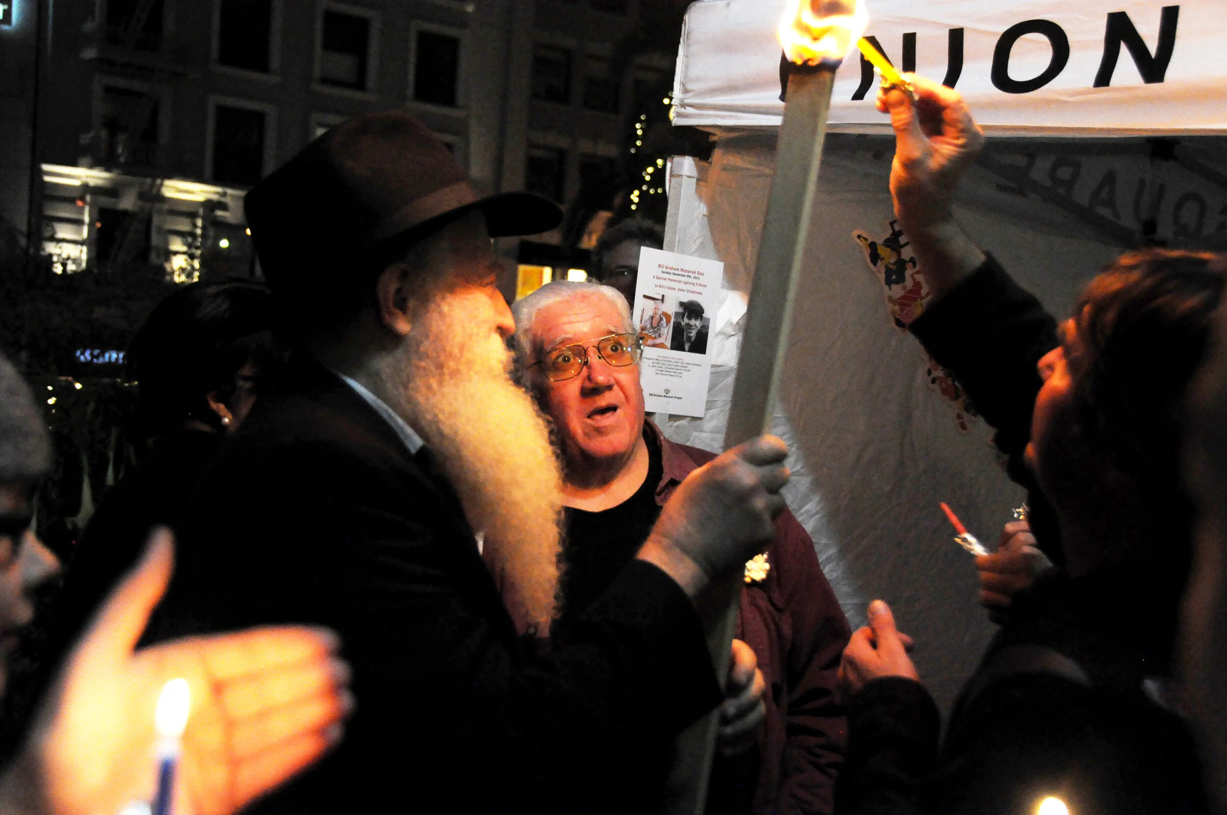 Rabbi Yosef Langer passes the torch during the Chanukah Festival of Lights in Union Square, San Francisco. © Beth LaBerge