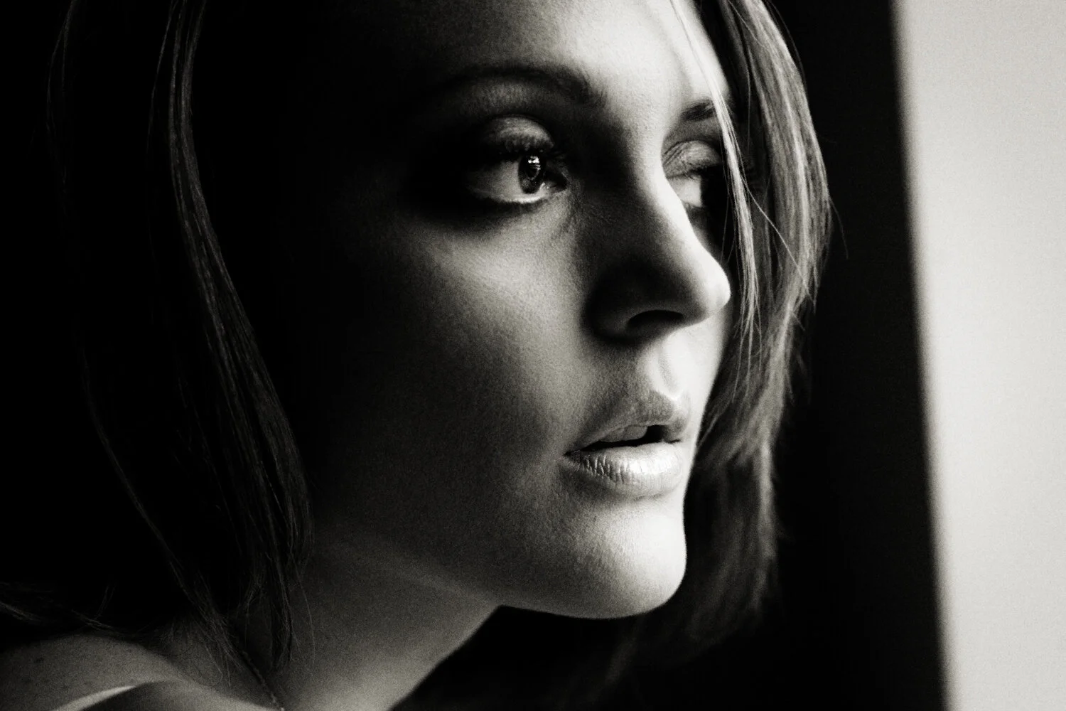  Black and white boudoir beauty shot. Close up of female face in dark and moody directional light.  