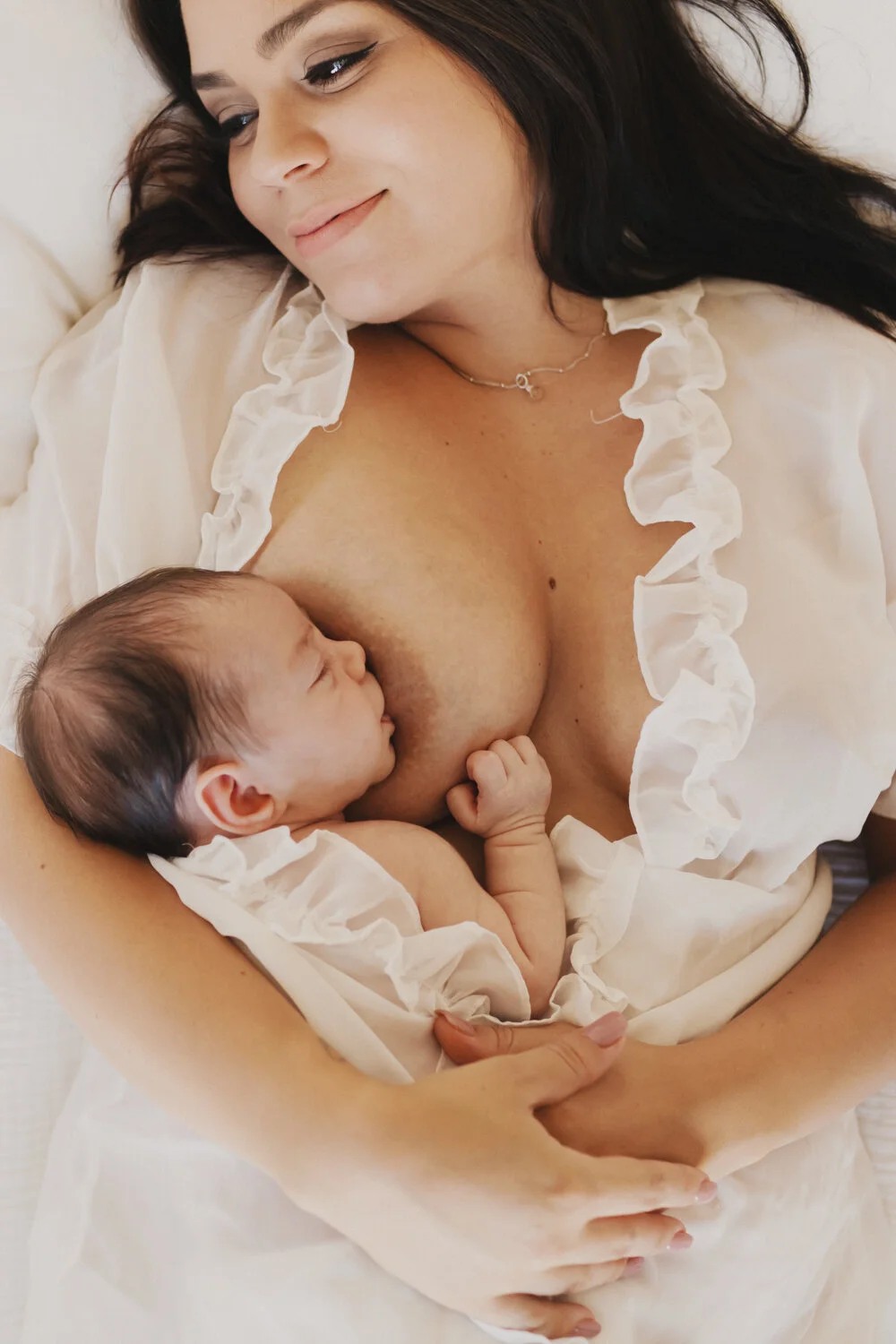  Motherhood boudoir. Nursing boudoir. Mother and infant daughter nursing in bed.  