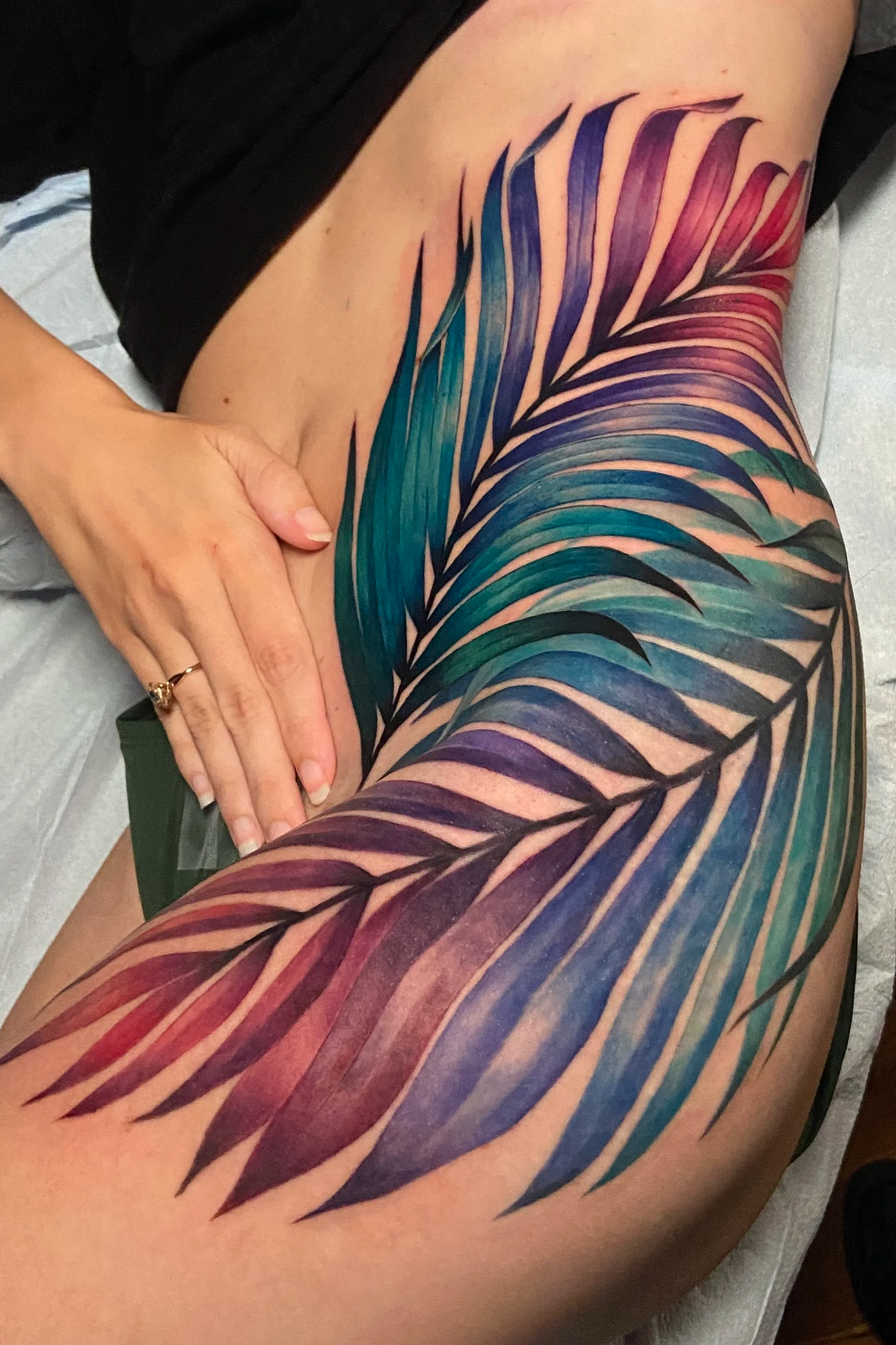 Adriana-hallow-tattoo-Melanated-skin-color-realism-nyc-rainbow-palm-frond-hip-thigh-piece.png