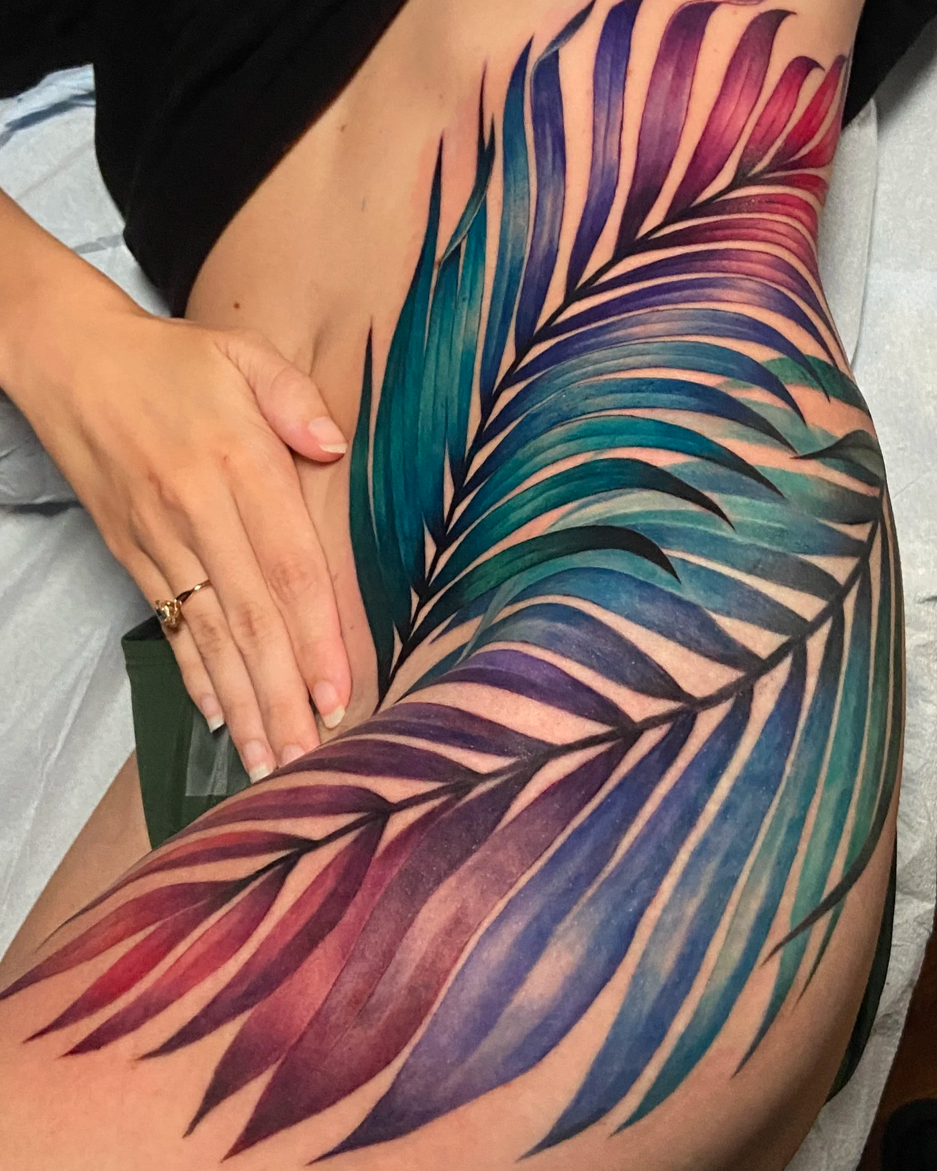 Adriana-hallow-tattoo-Melanated-skin-color-realism-nyc-rainbow-palm-frond-hip-thigh-piece.png