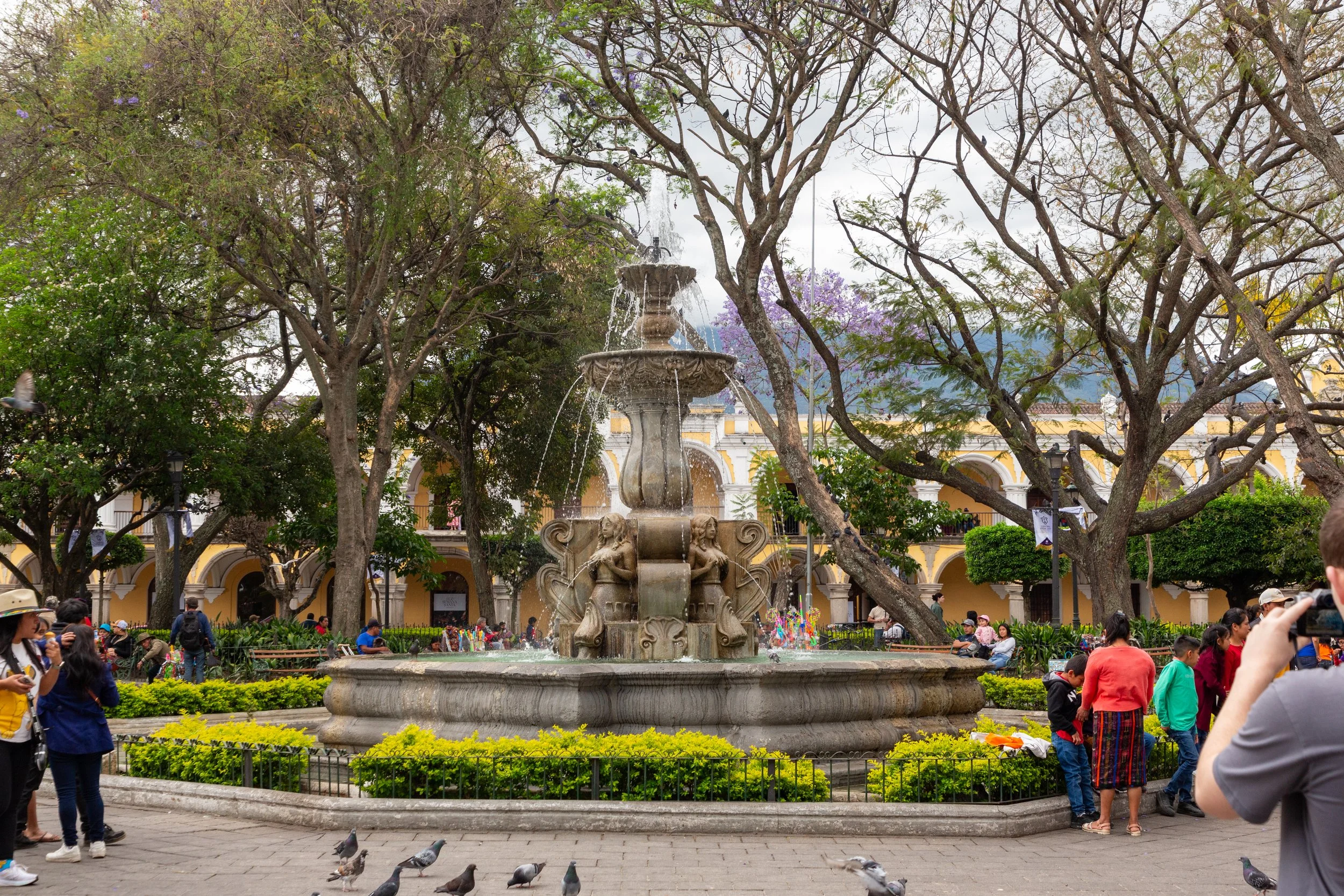  The Fountain of the Mermaids, in Antigua’s Central Park, full of visitors relaxing and having ice cream 