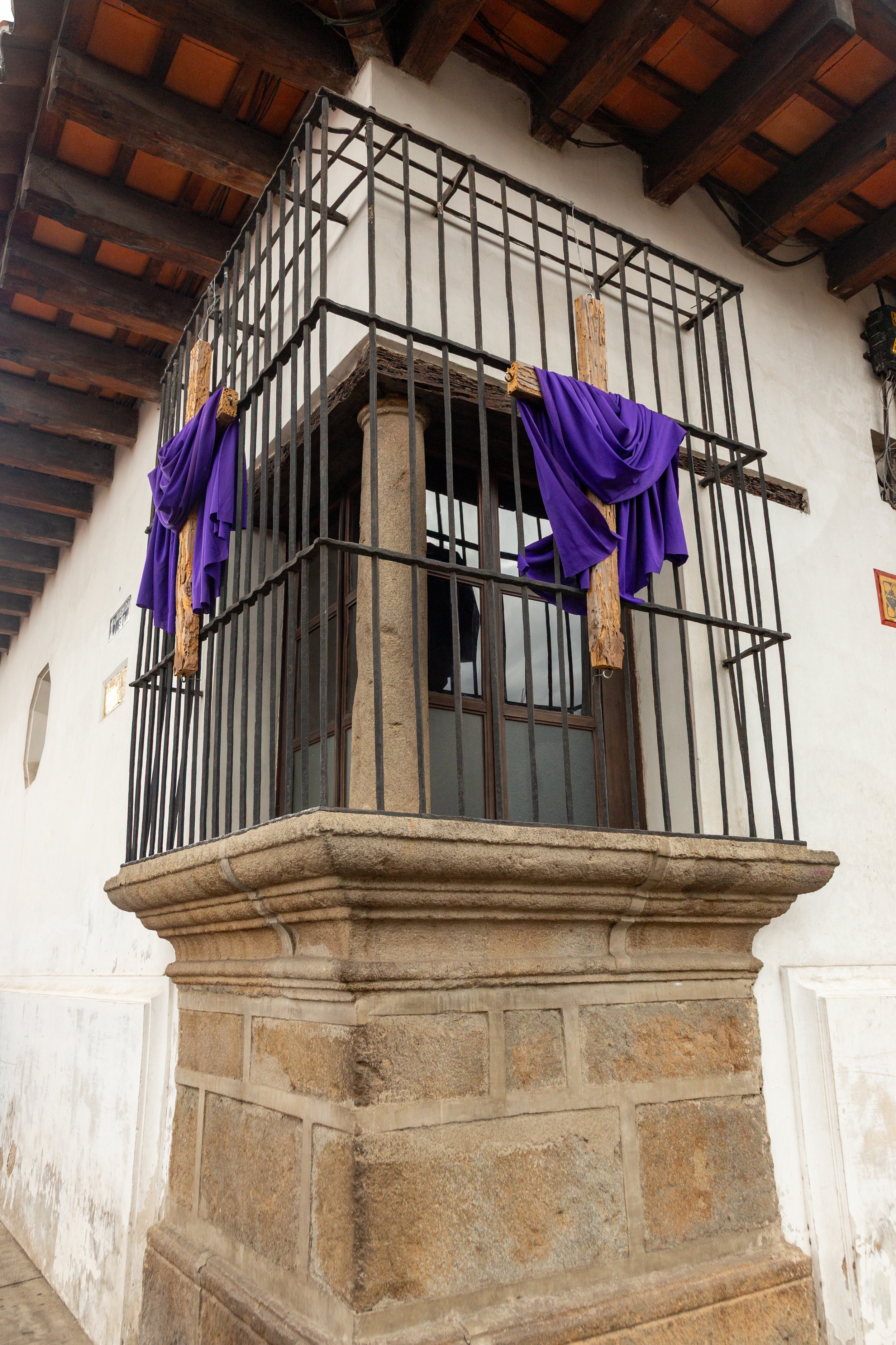  This Good-Friday-decorated corner window with wrought iron bars allows residents to look down both intersecting streets 