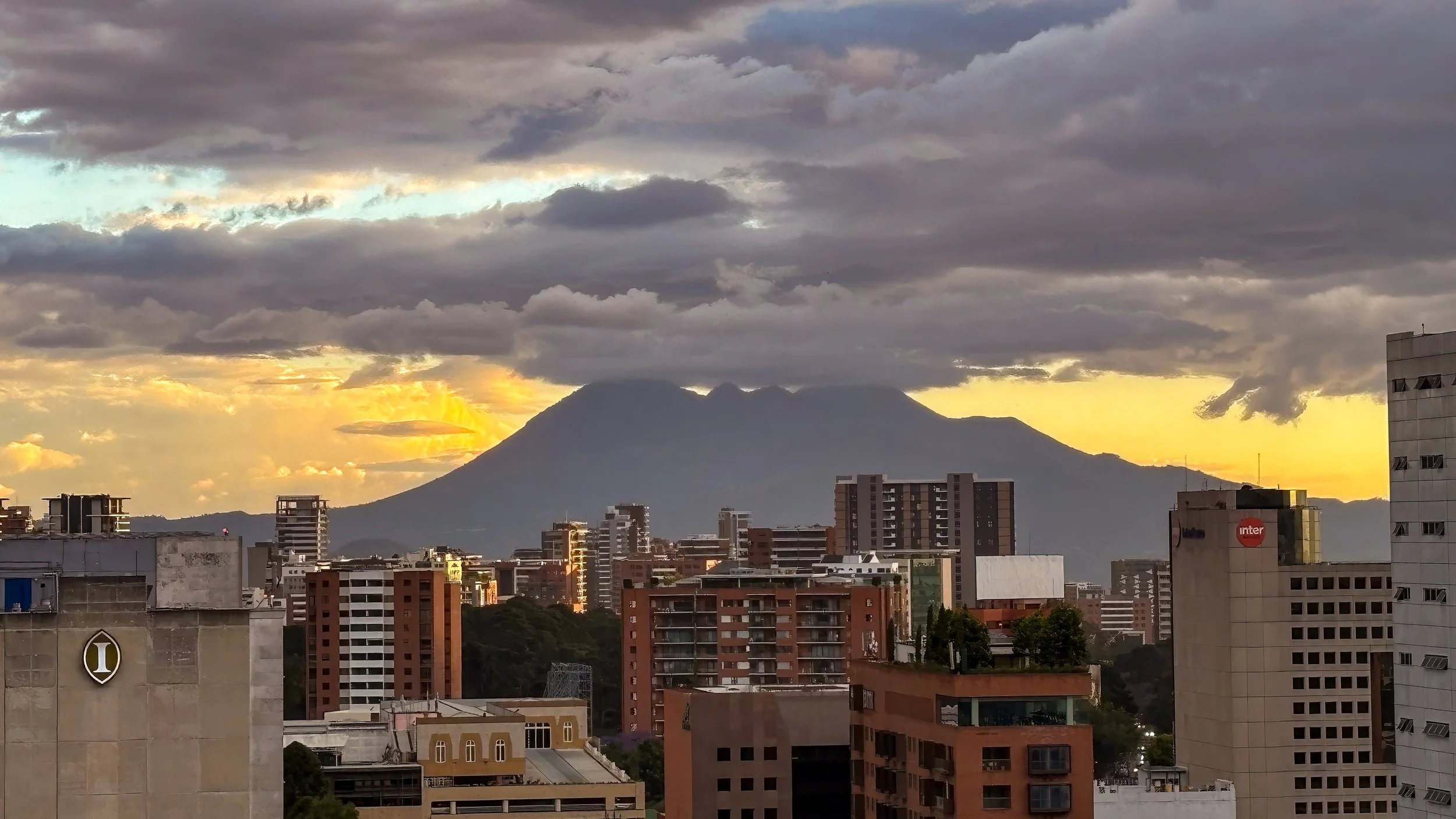  Having been driven back to Guatemala City, now back at the rooftop pool of our hotel, the Pacaya volcano makes its first appearance for us 