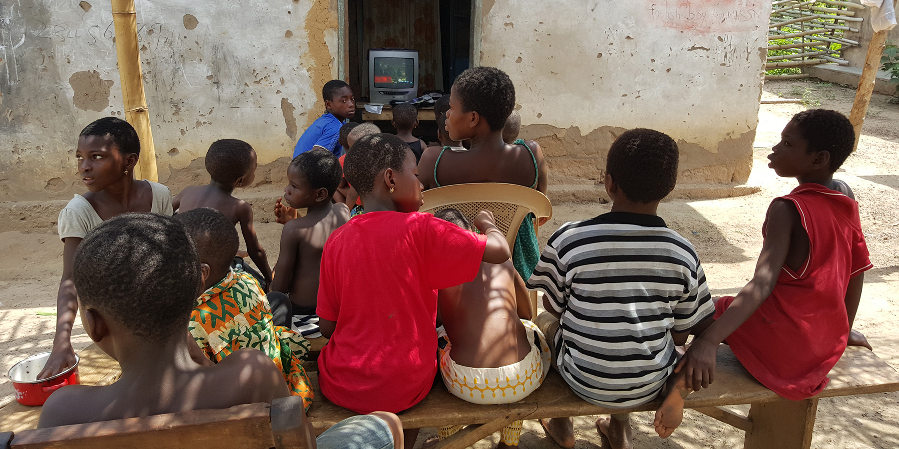 Young people gather to watch a TV show from an old box television set in rural Africa. 