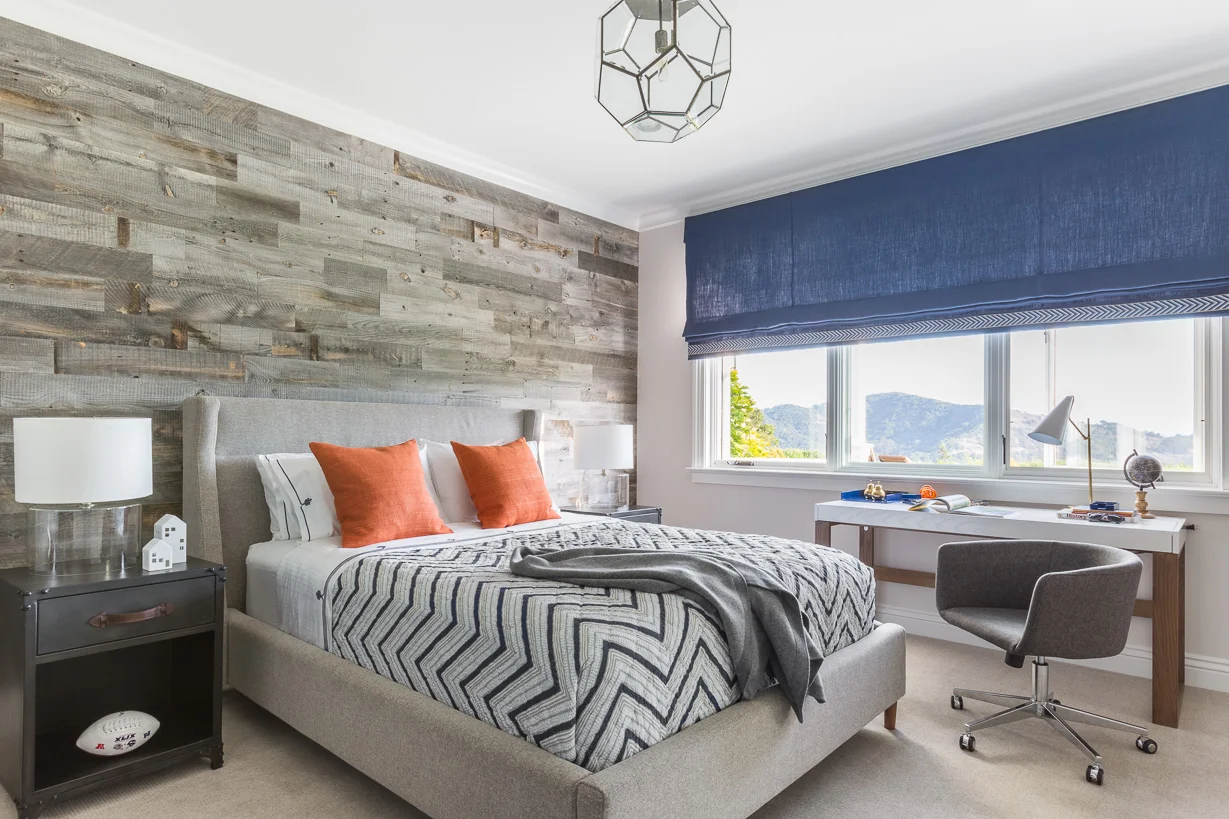 In the ten-year-old son’s room, the headboard wall features a faux-bois covering by Stikwood. The ceiling pendant and bedside tables are by RH.