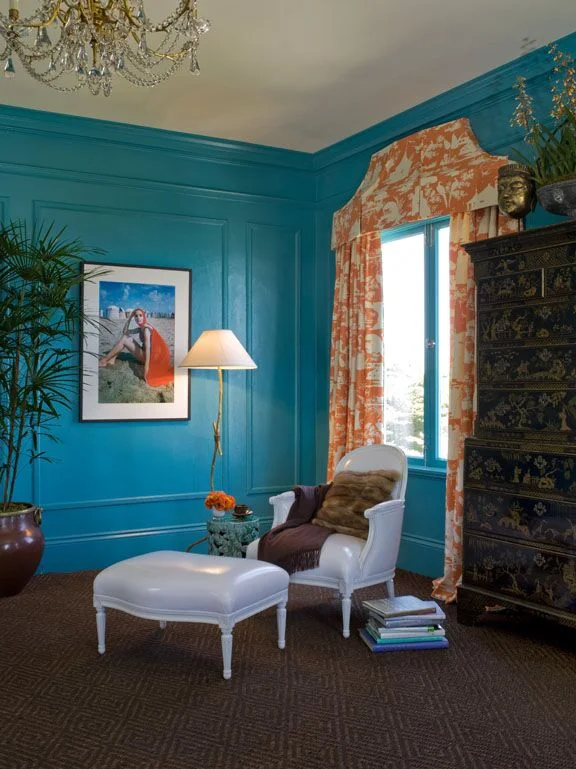 Kendall Wilkinson Design painted these bedroom walls teal blue. Orange accents and coral toile fabric add drama.