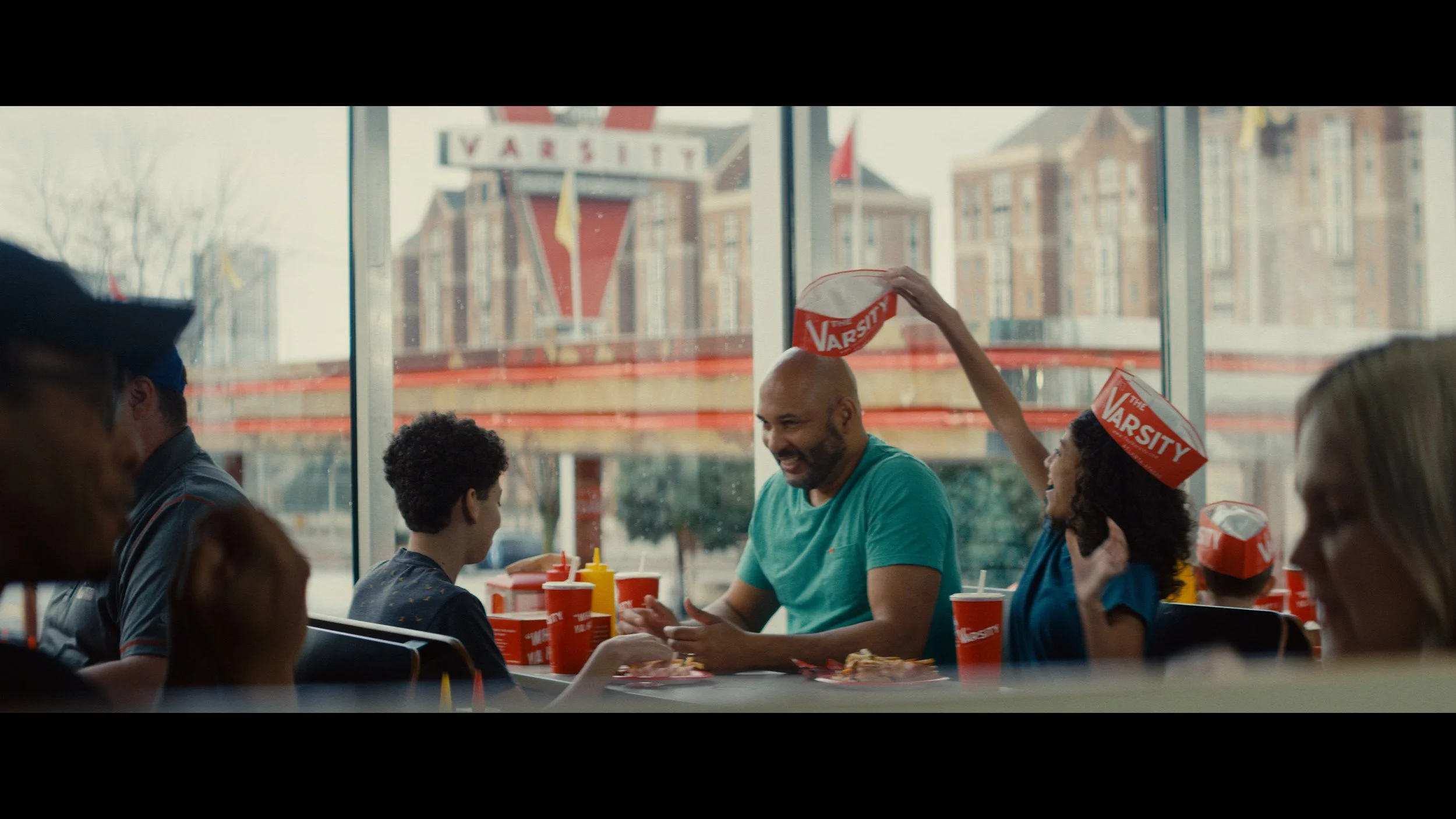 Diners at a table inside The Varsity in Atlanta, red paper hats and cups on the table. Cinematography by Mick Hawkins.jpg