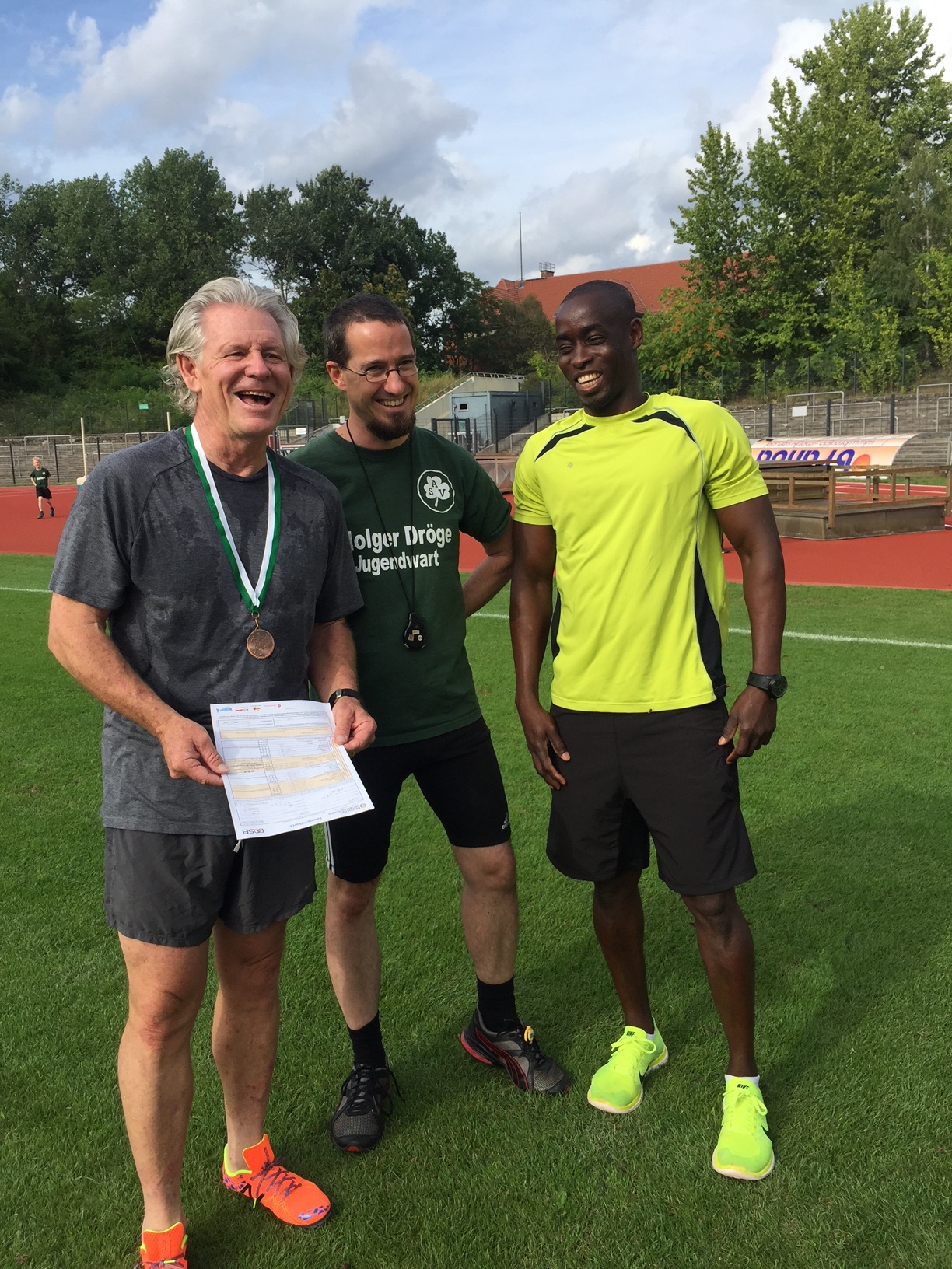 Here Club Trainers Droege and David give me grief about the slow 100m and 200m times that were recorded forever in the ASV Berlin Athletics Club official register. Oh, and the medal was awarded to me by the club.