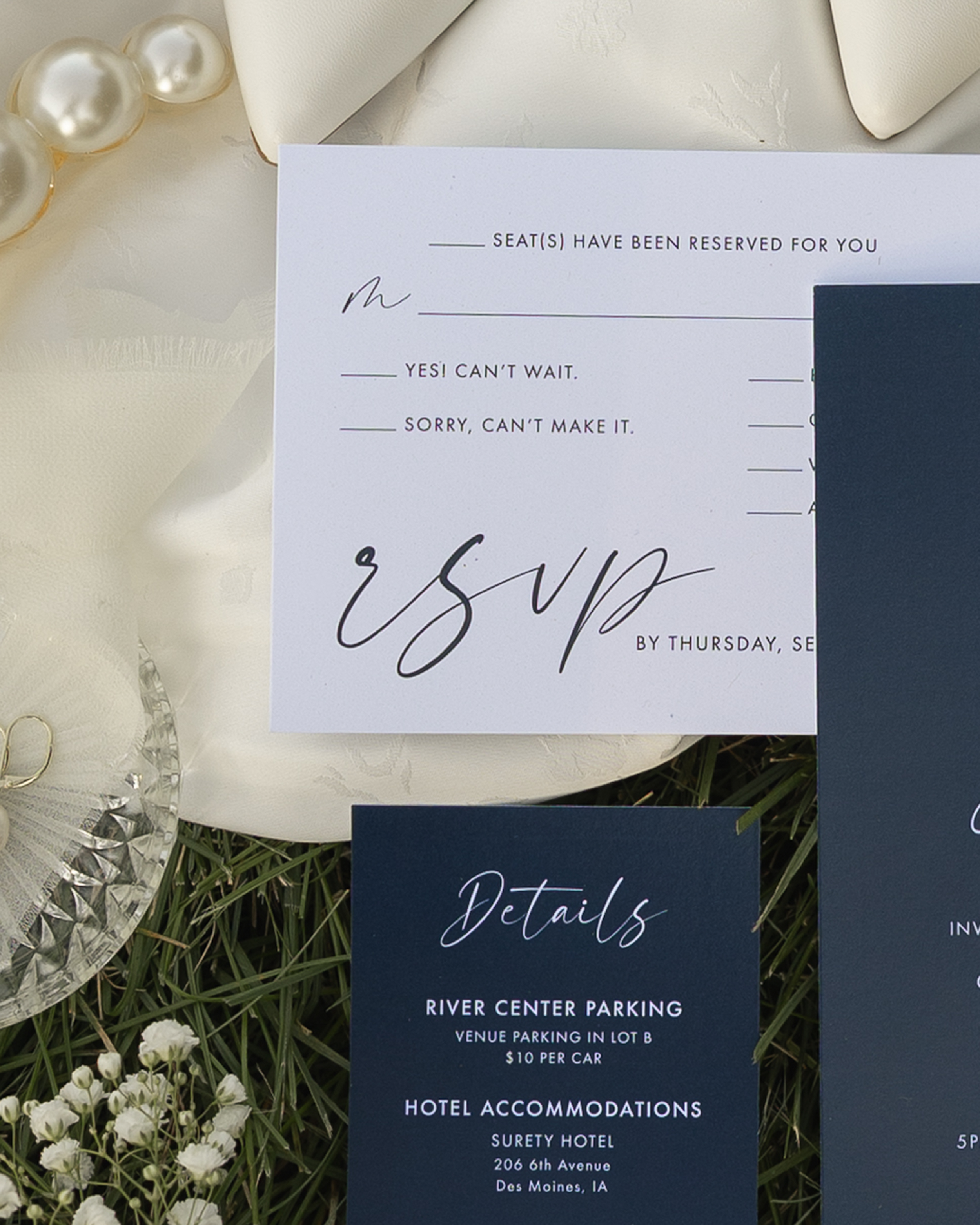 Reserved seating card with white and navy blue sections, flowers and pearl decorations, and event details including hotel and parking information.