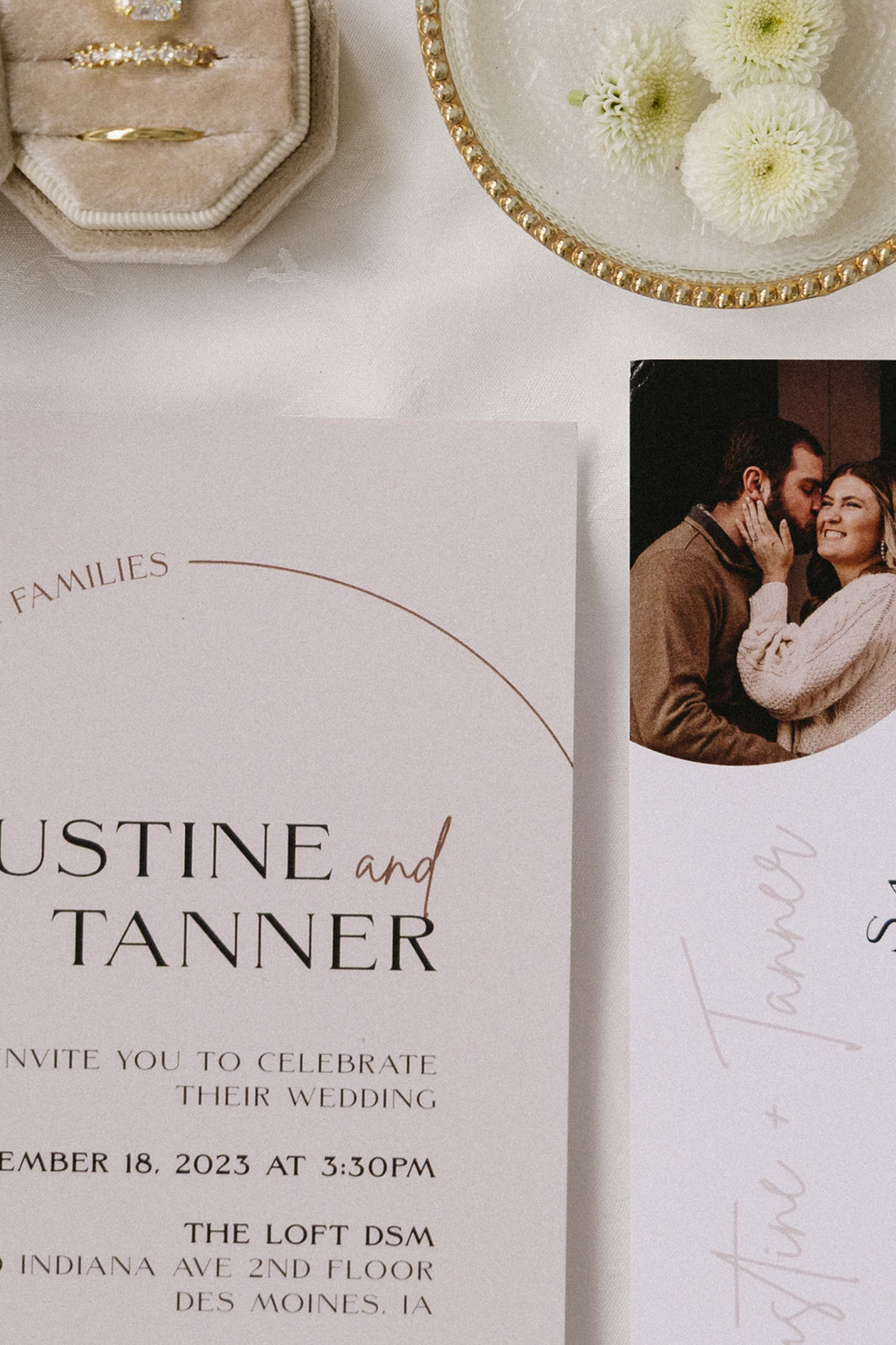 Wedding invitation for Austin and Tannner, with a photo of a couple, a small flower arrangement, and jewelry.