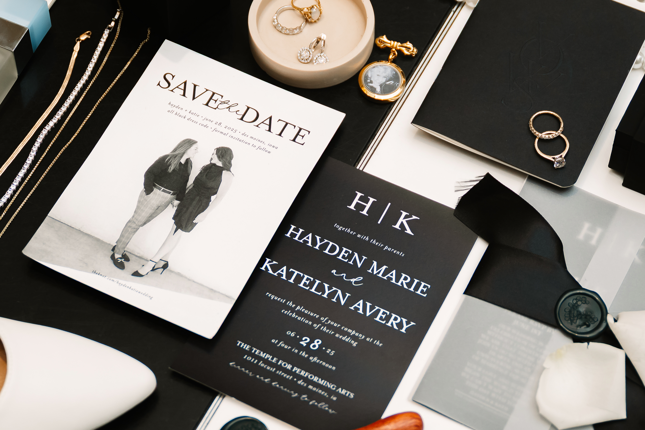 Wedding invitation cards, jewelry including rings and earrings, and decorative items displayed on a table.