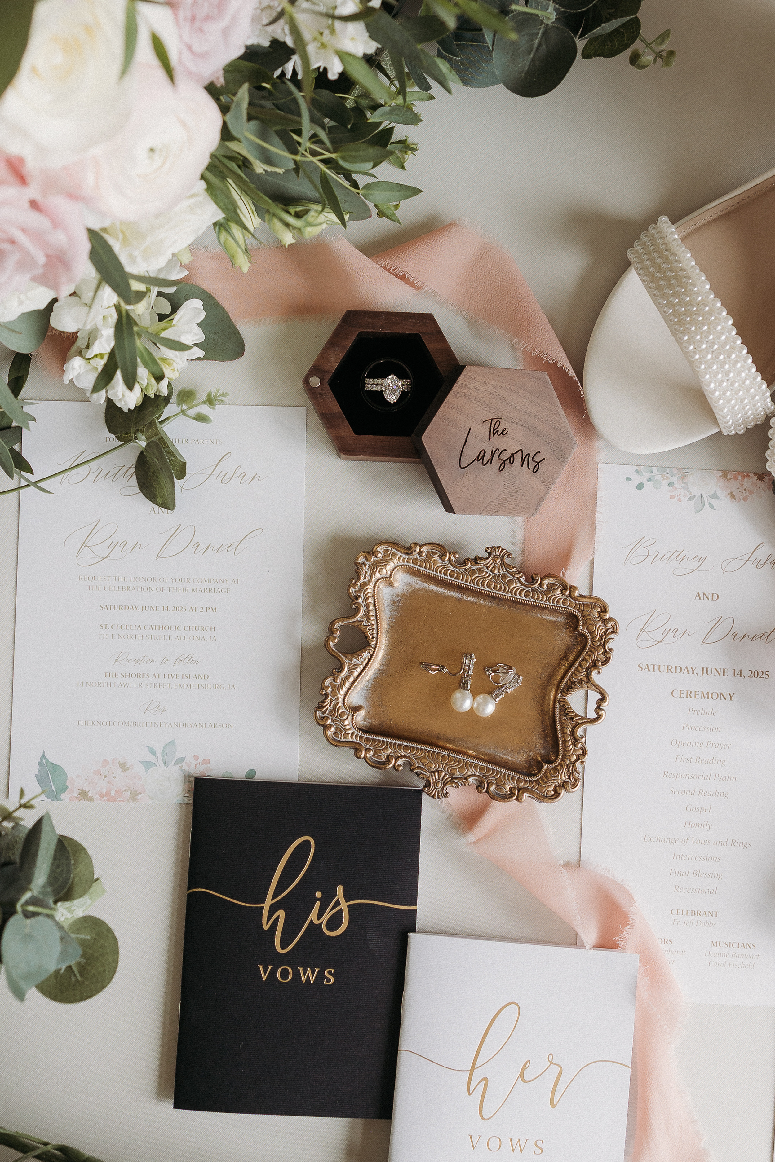 Wedding vow books, a flower arrangement, jewelry in a wooden box, and a ceremony program on a table.