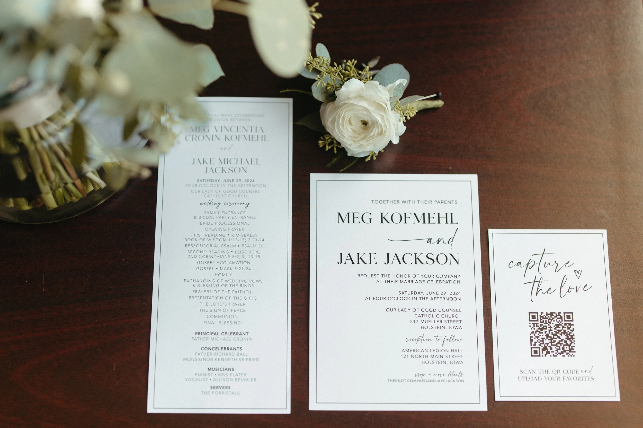 Wedding program cards with floral decoration and QR code on a dark wooden table.