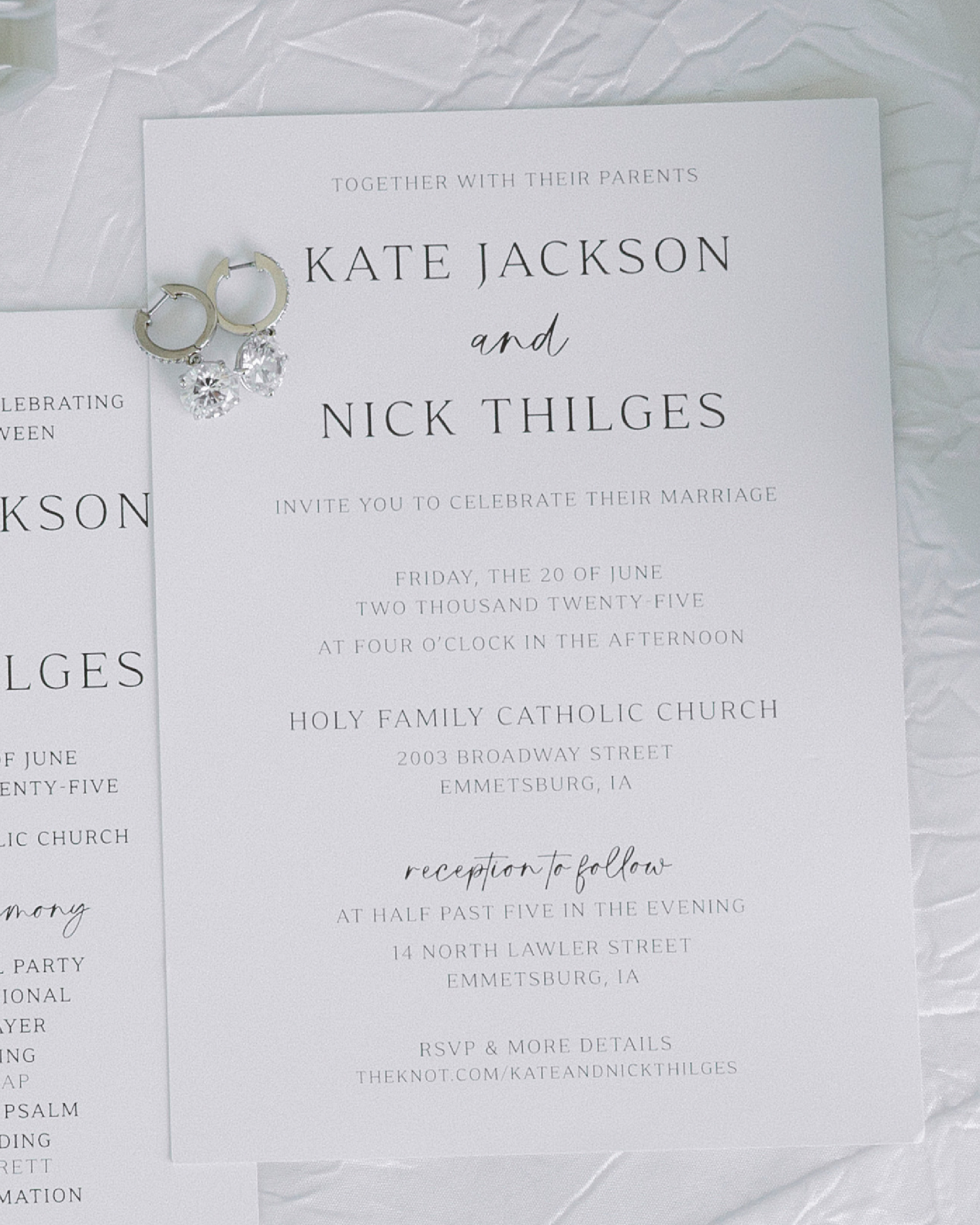 Wedding invitation for Kate Jackson and Nick Thilges, with silver hoop earrings featuring dangling crystals, placed on crinkled white paper.