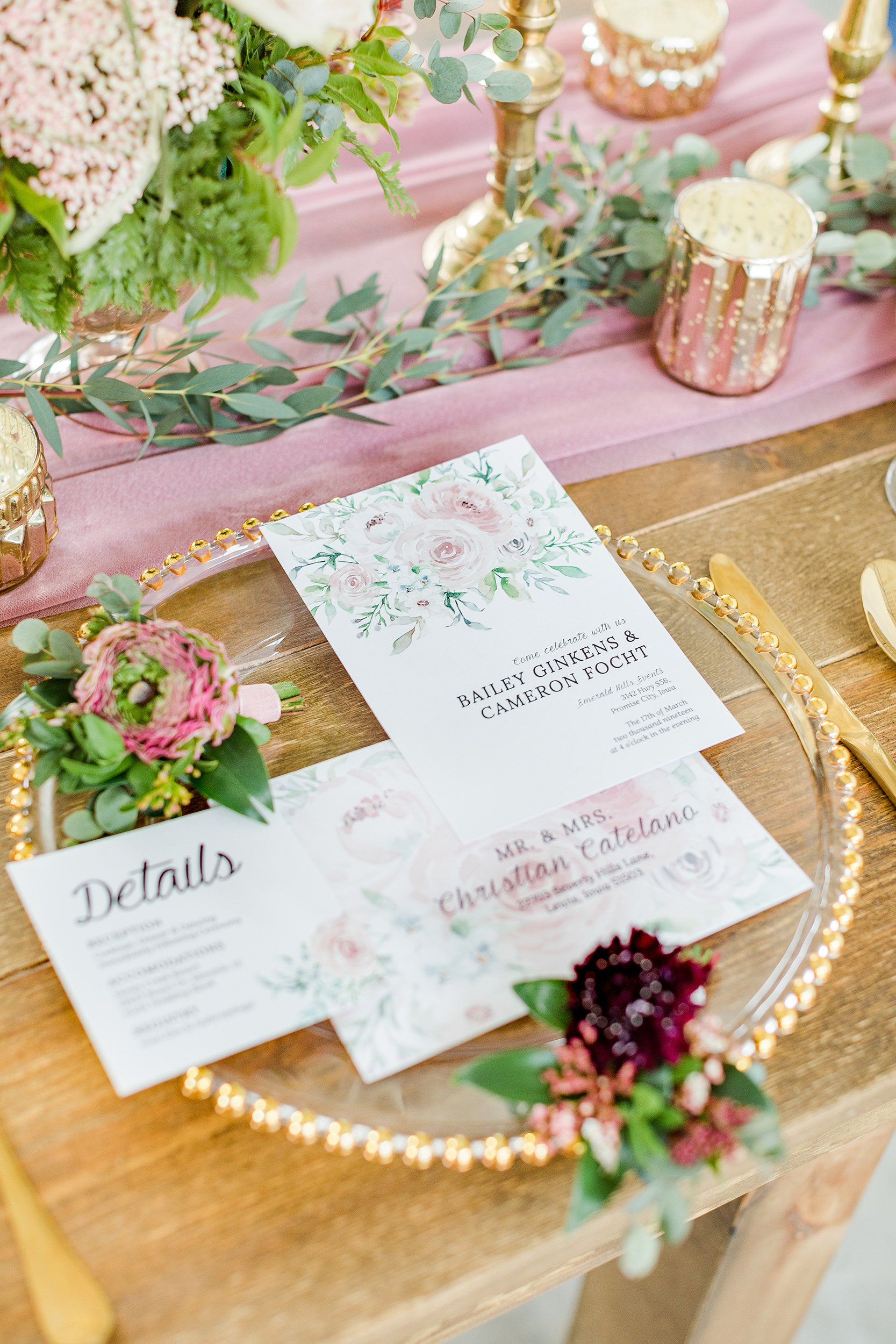 Wedding or event table decor with floral arrangements, pink candles, and a wedding invitation for Bailey Ginkens and Cameron Focht.