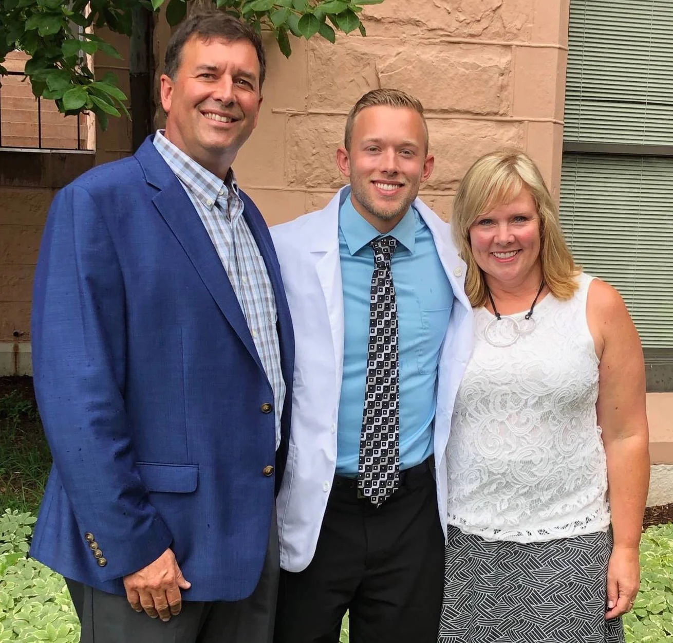 Luke with his parents at his white coat ceremy
