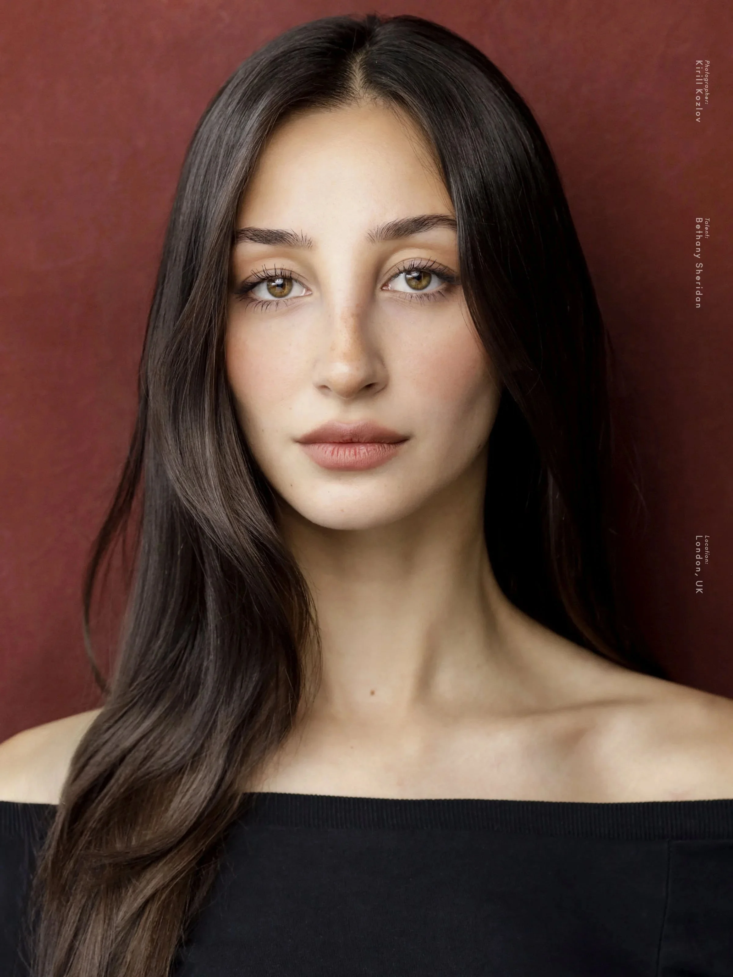 Bethany Sheridan — actor headshot, dark hair loose against an oxblood backdrop — photographed by Kirill Kozlov, North London.