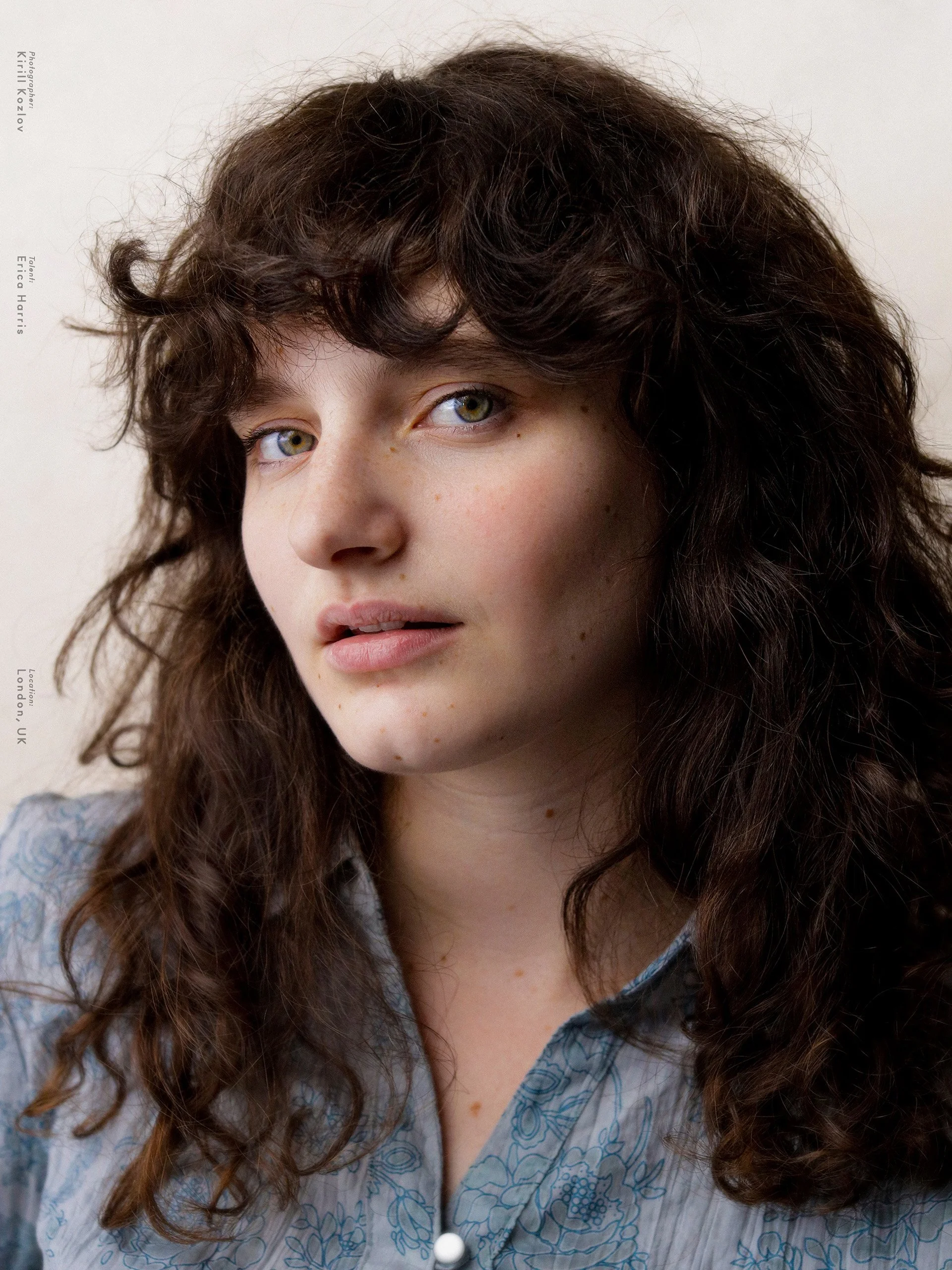 Erica Harris — actor headshot, dark curls loose and a soft floral collar against a pale wall — photographed by Kirill Kozlov, North London.