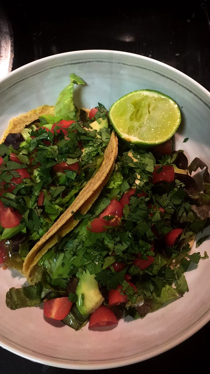 Refried beans, lettuce, cilantro, cherry tomatoes, avocado, lime, tomatillo salsa.