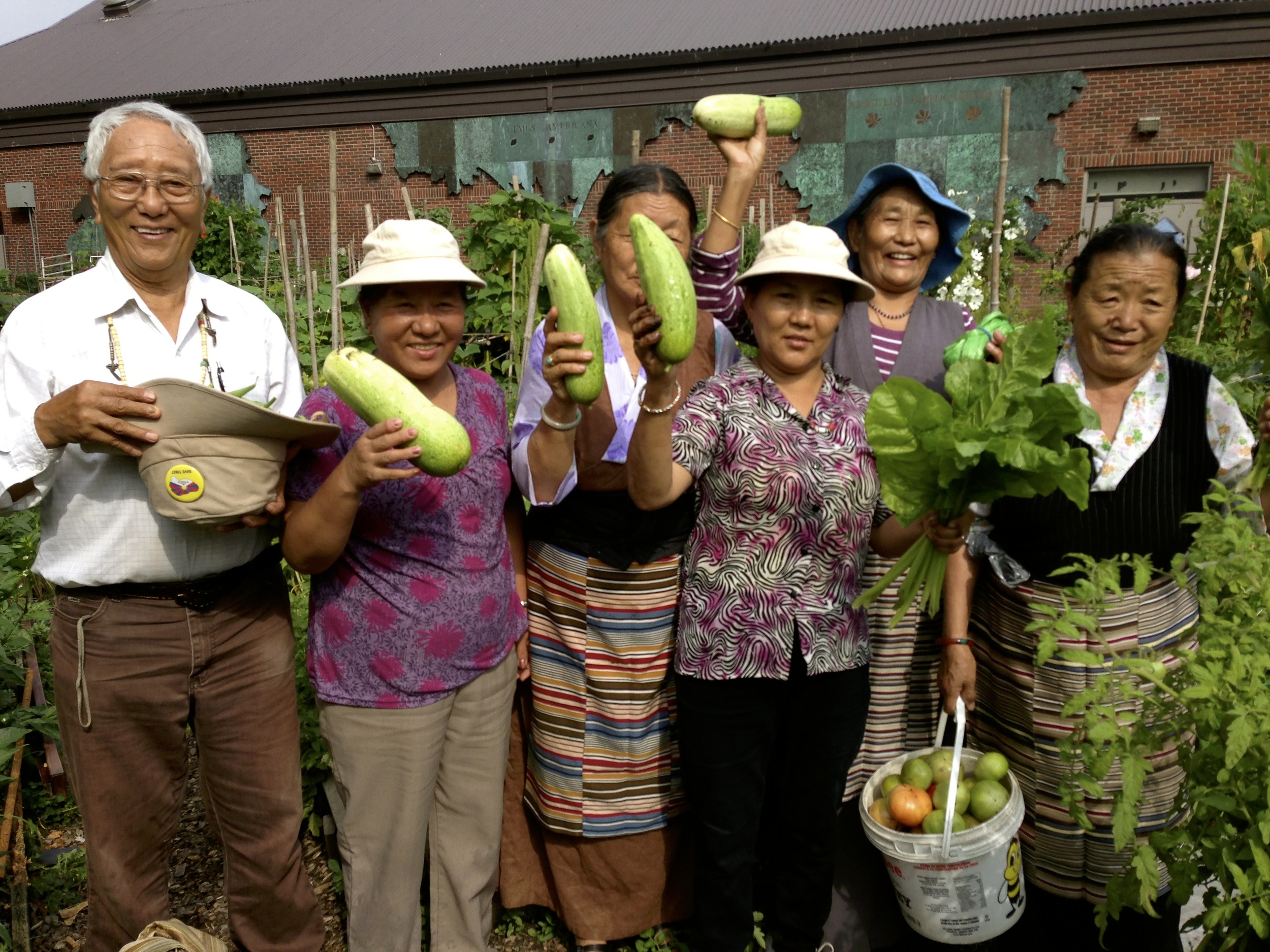  A group of people smiling and holding up produce in the HOPE Community Garden 