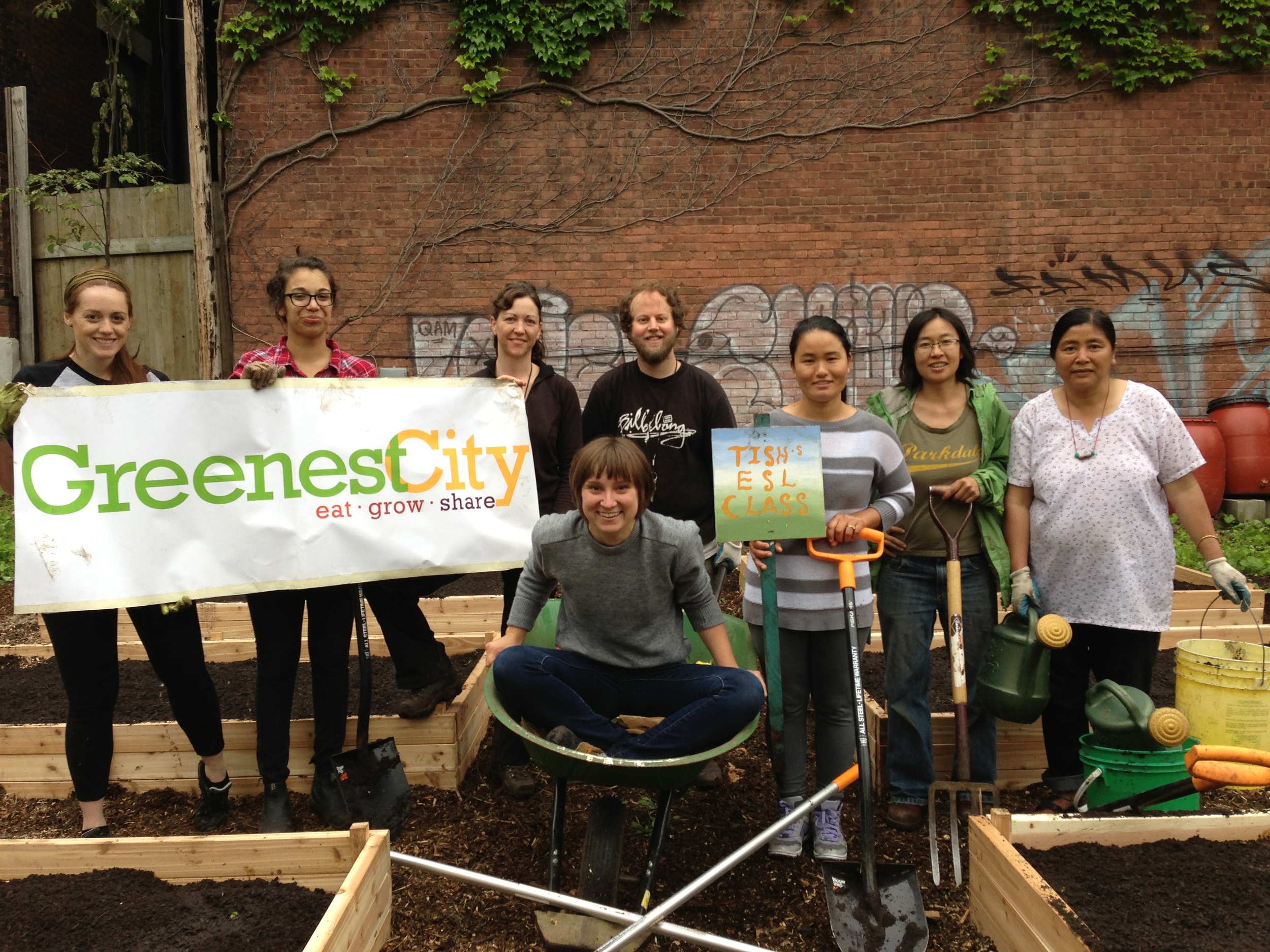  A group of people in the Milky Way Garden smiling and holding up a Greenest City banner 