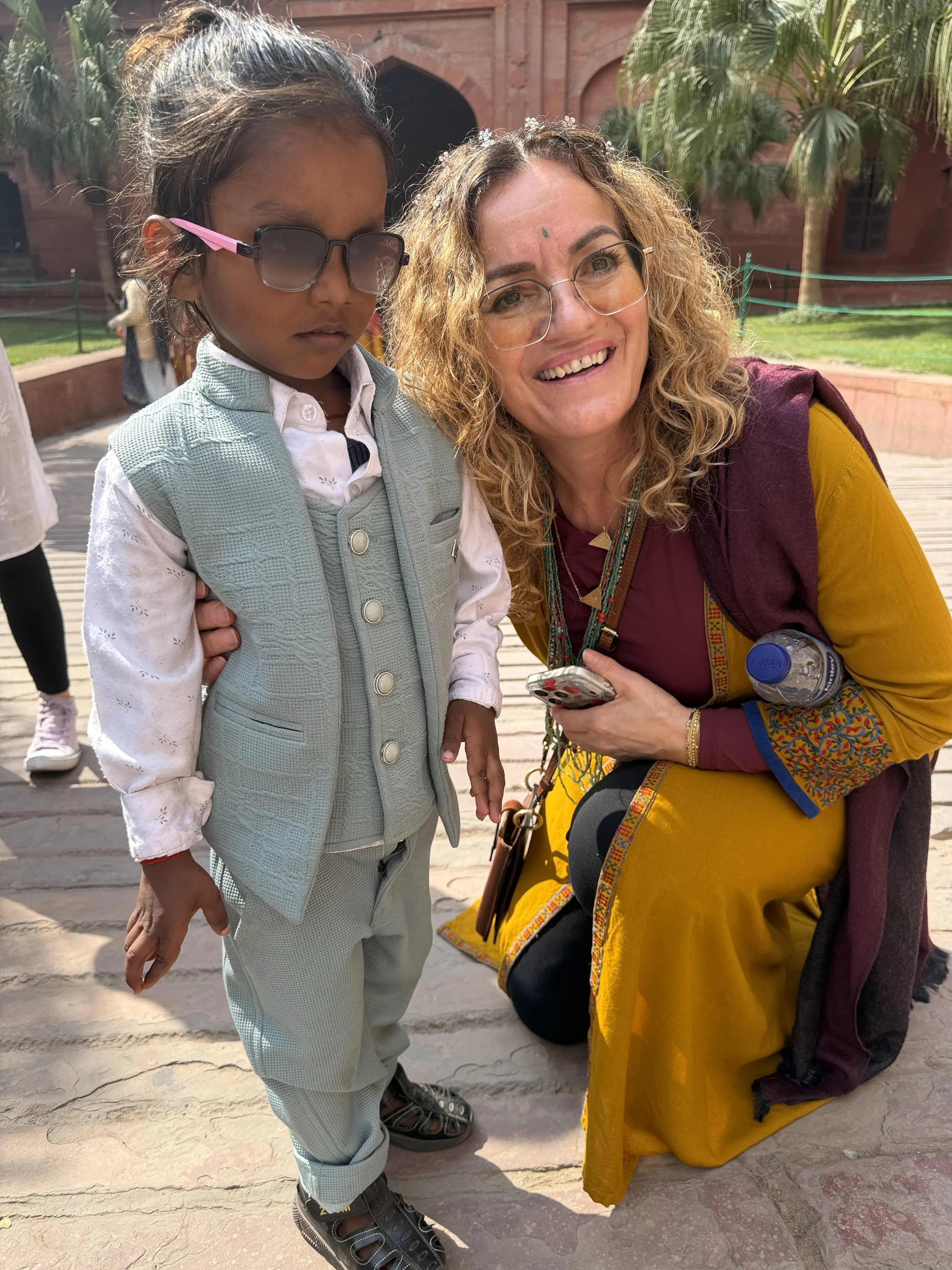 Outer Banks Yoga retreat participant smiling alongside a local child during a cultural immersion journey in India.