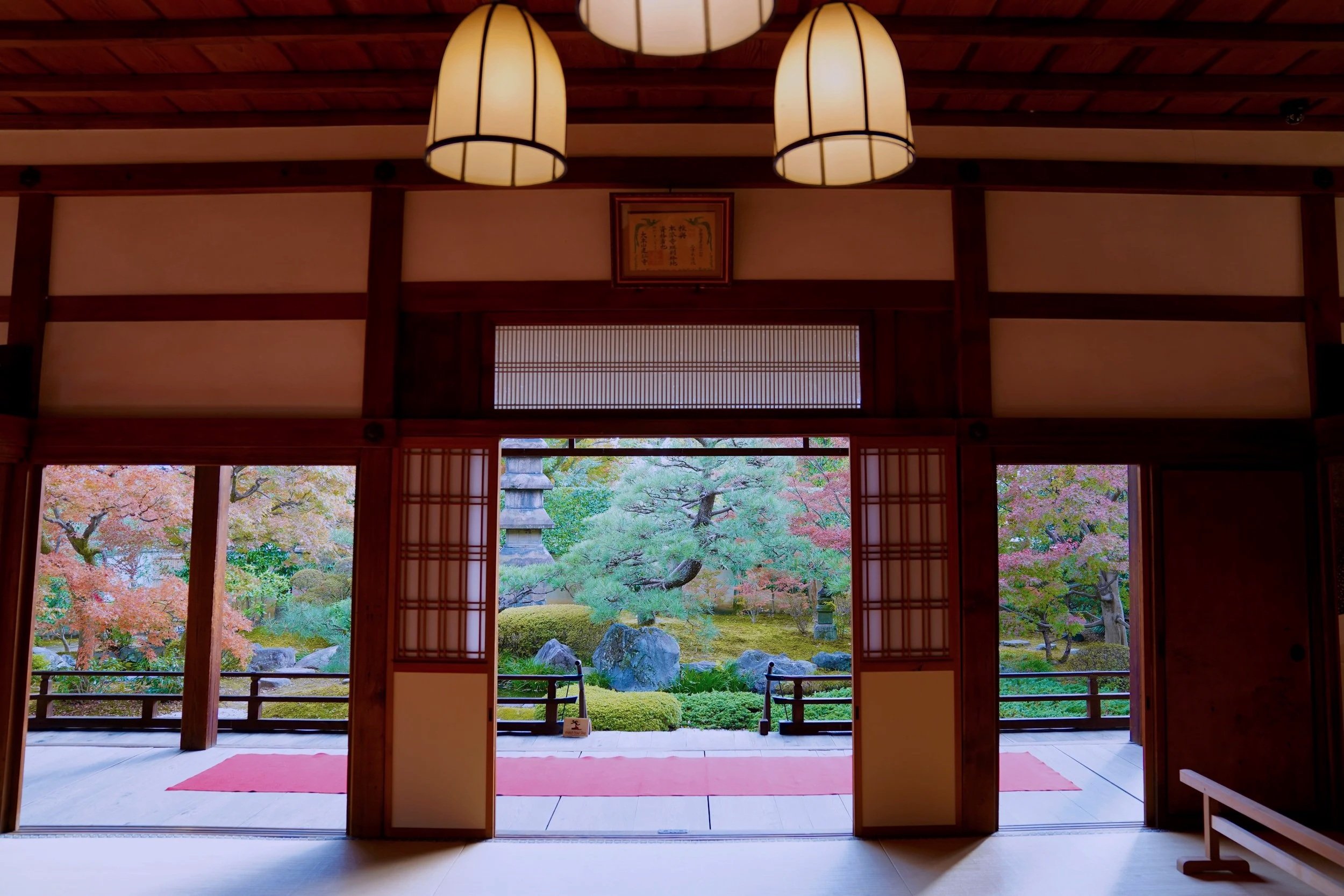 A quiet traditional Japanese temple interior looking out onto a green moss garden, reflecting Zen philosophy and mindfulness travel.