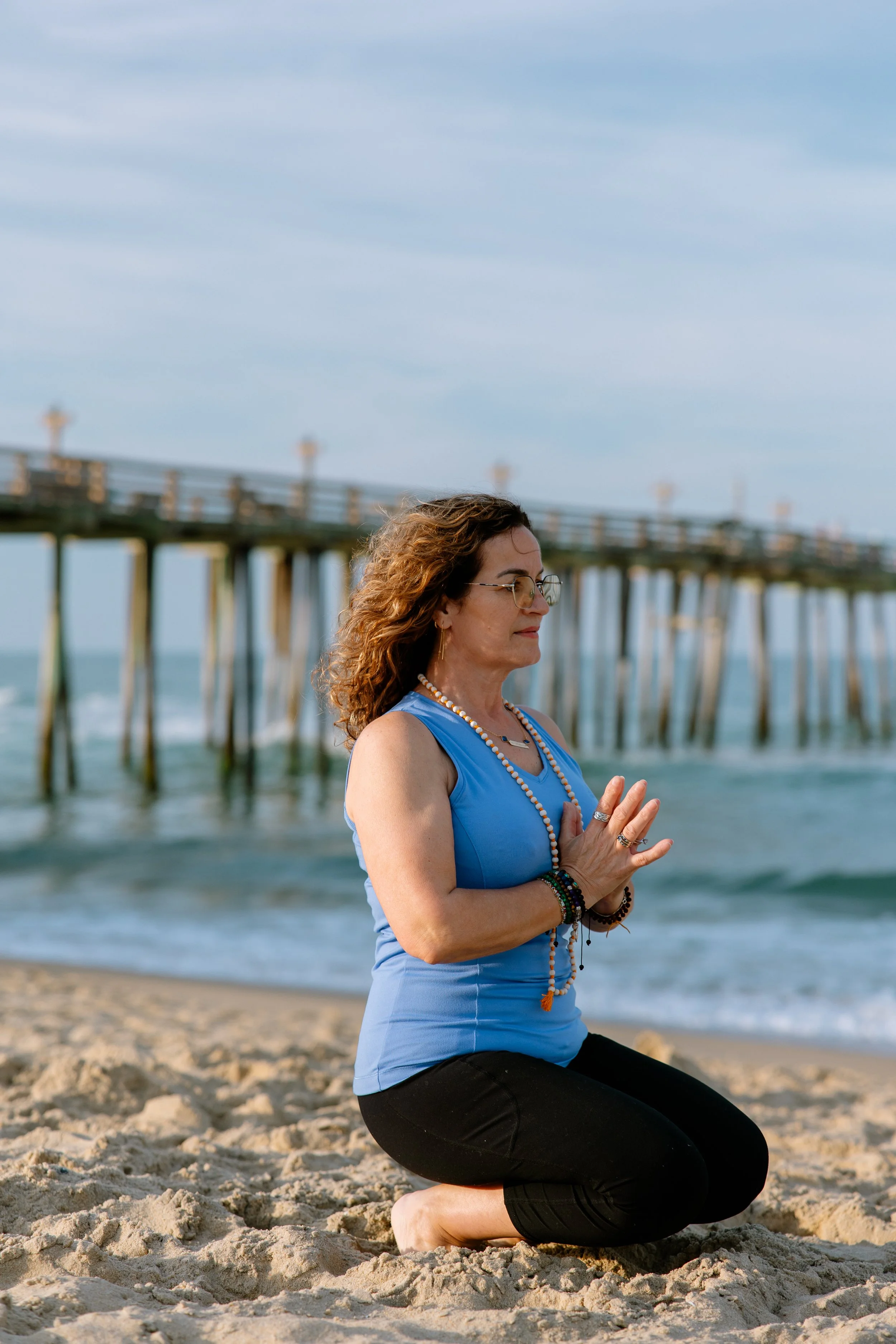 Yoga instructor Oli Cela practicing a seated prayer pose on the beach.