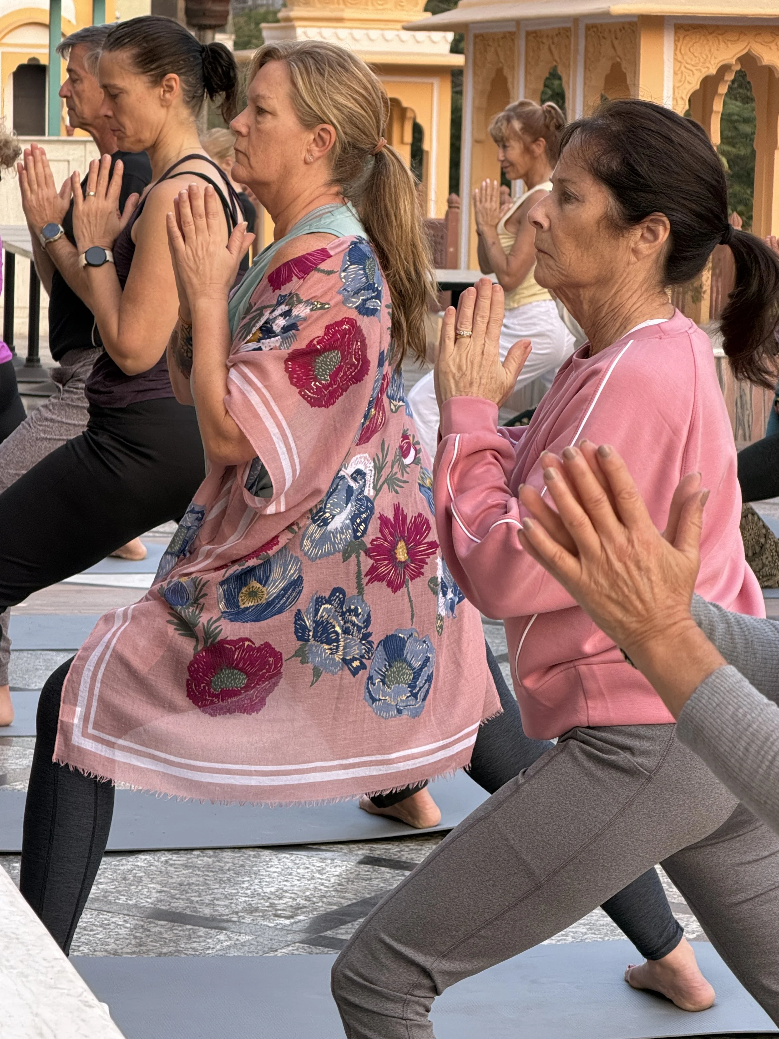 women and men practicing yoga with their hands in prayer position during a culture and wellness retreat in Jaipur India