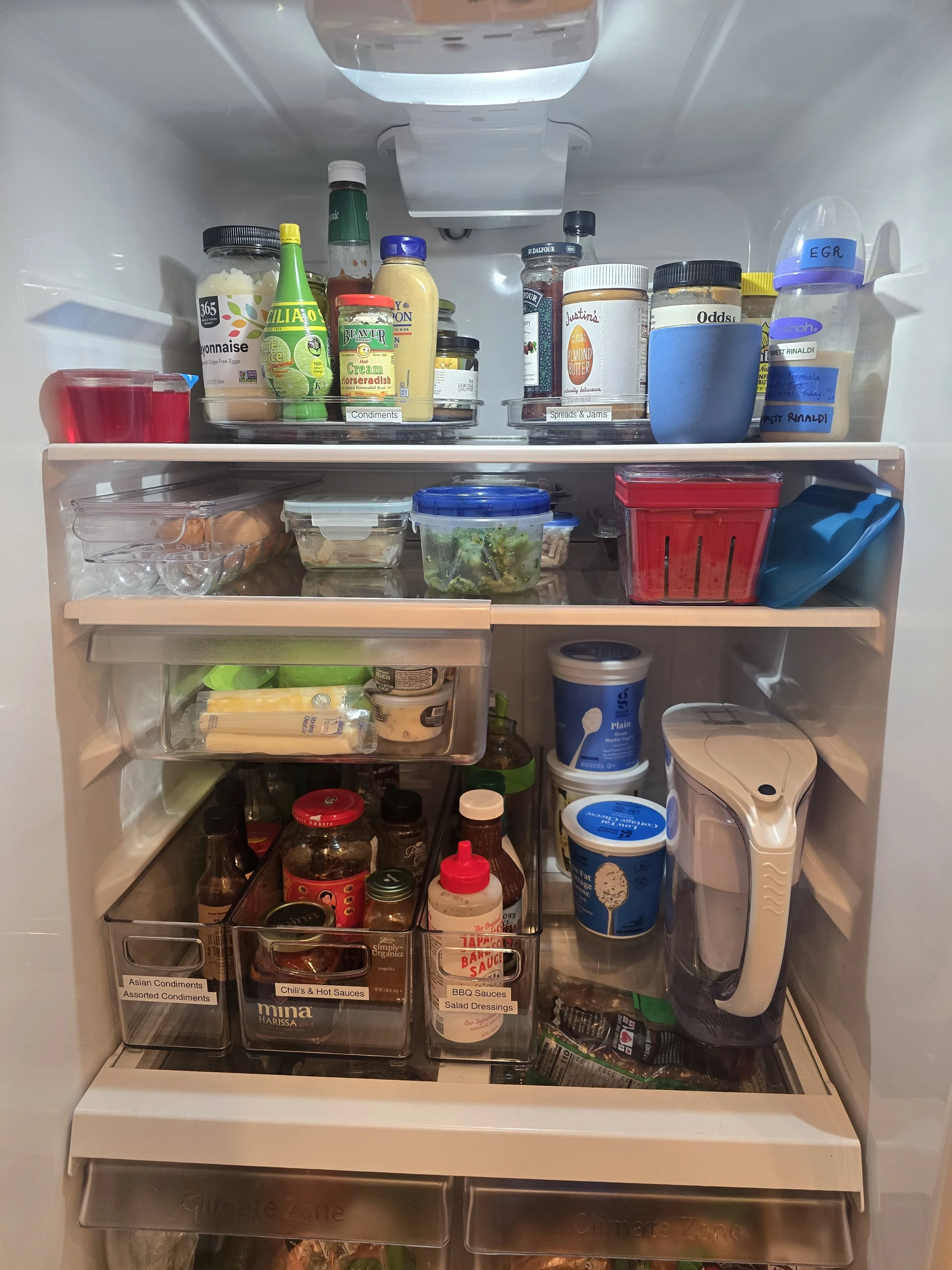 Open refrigerator with various condiments, sauces, jars, and food containers