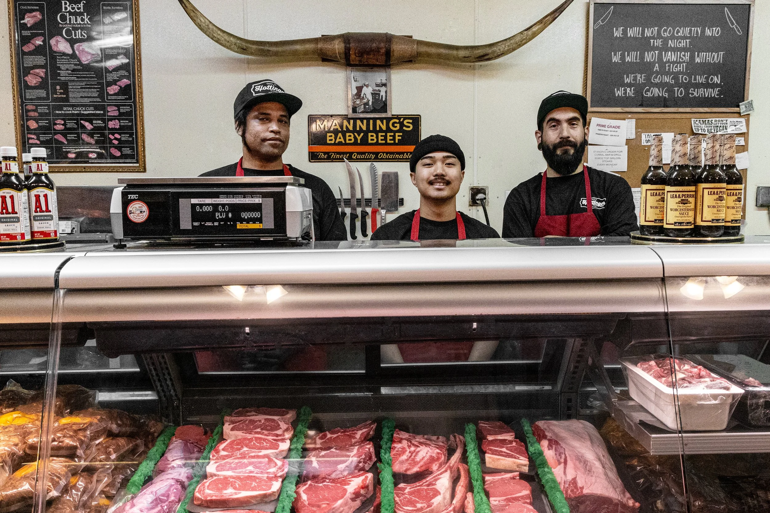 Photograph of three employees behind meat case.  From left to right: Cahnan, Shamrock, and Frankie.