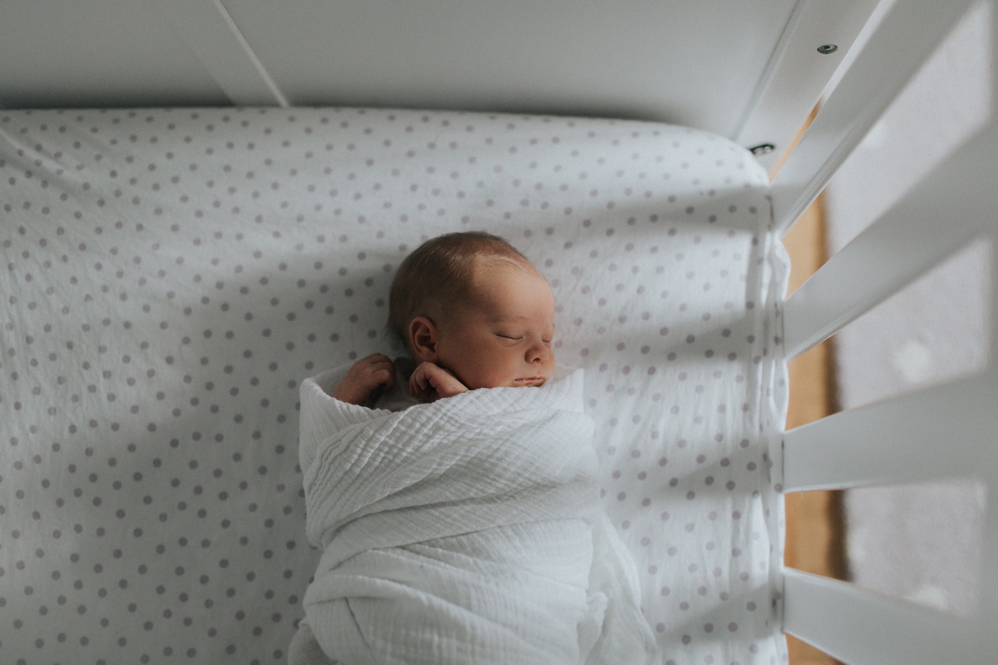 Lauren Giuffre is the premier Boise Idaho Newborn Photographer, an image of a beautiful newborn wrapped up in a crib