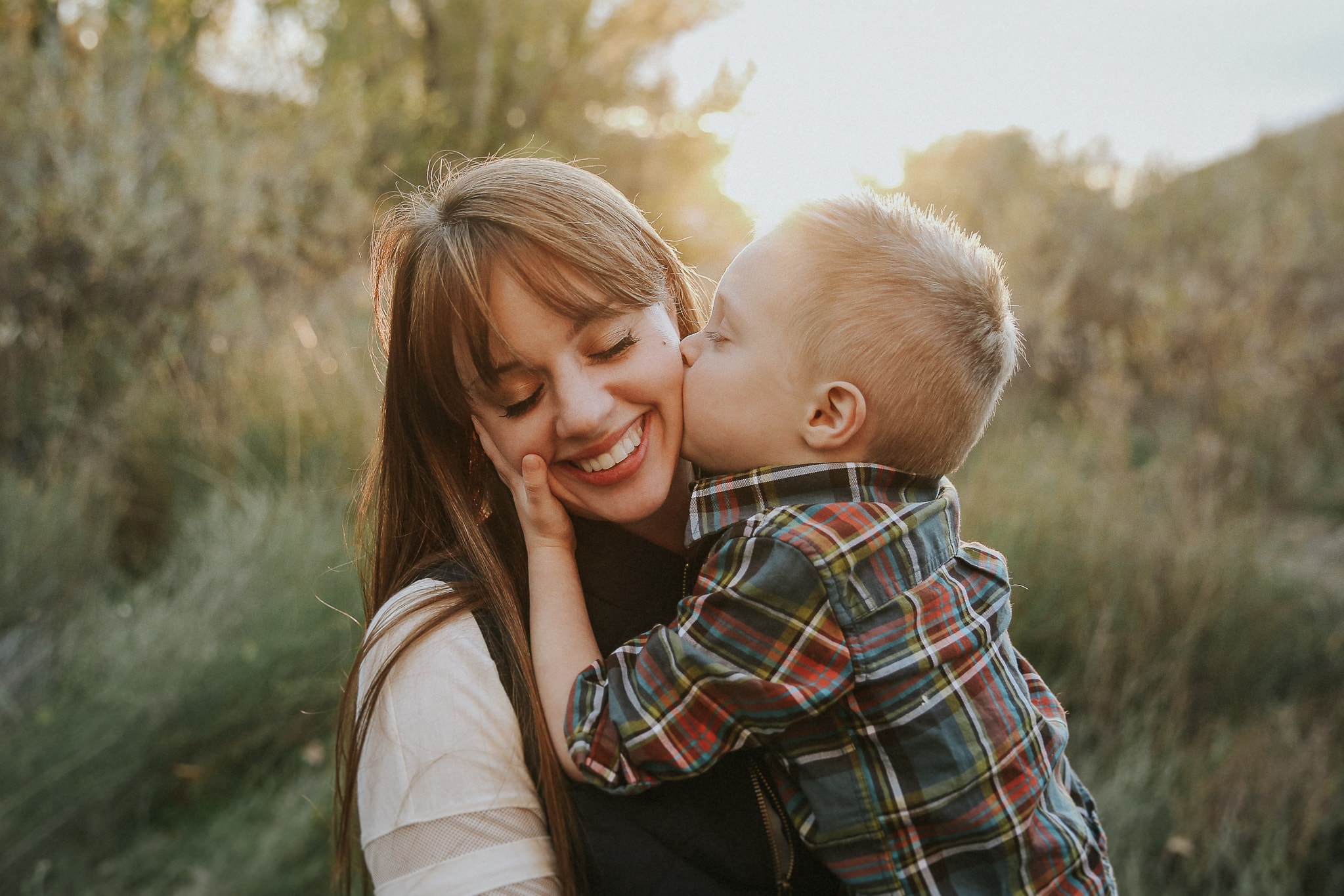 A tender moment between a mother and son, with the young boy kissing his mother cheeks, photographed by the premier Boise Idaho family photographer, Lauren Guiffre