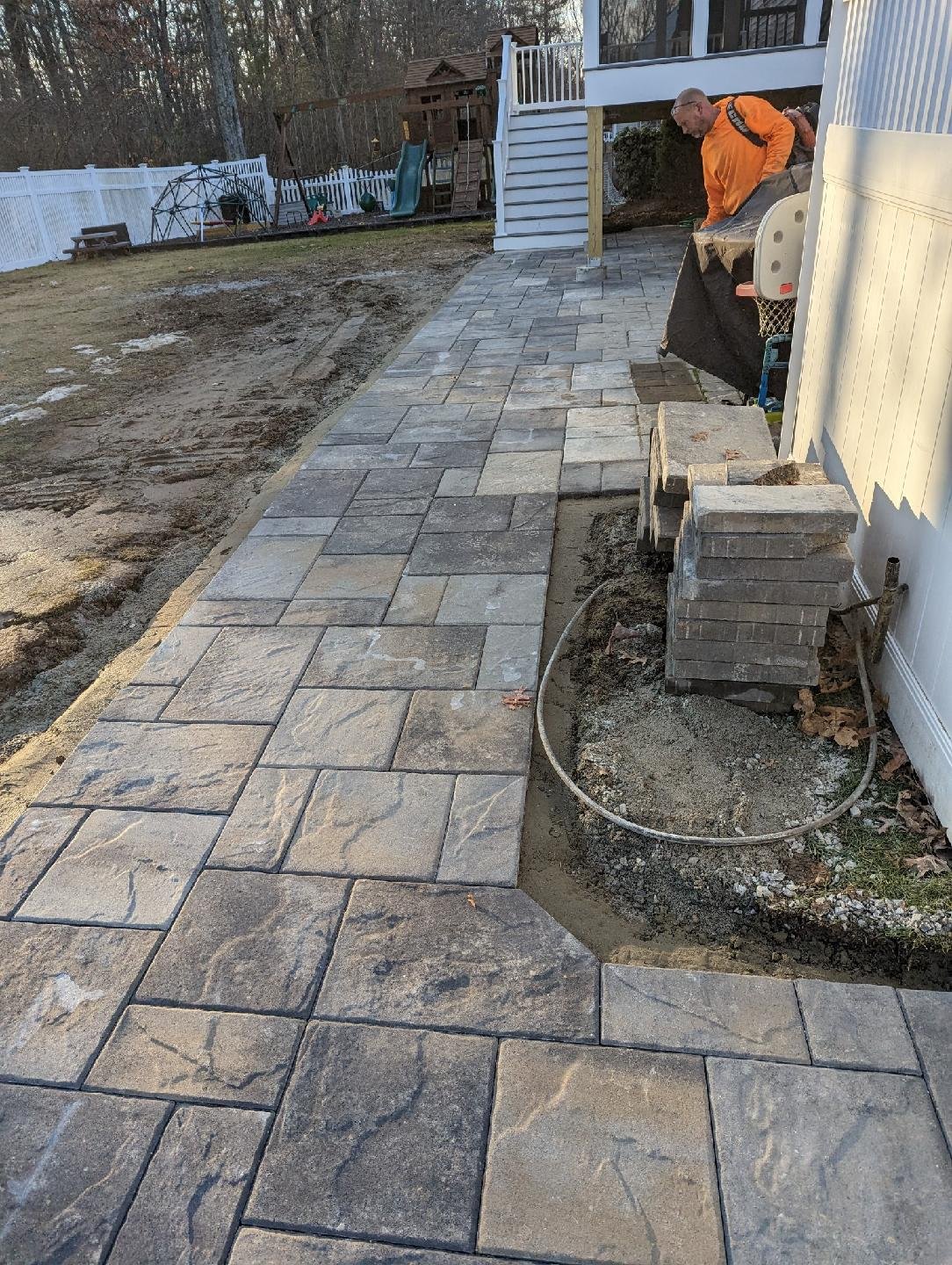 Paver patio installation beneath three-season screen room in Ashland MA