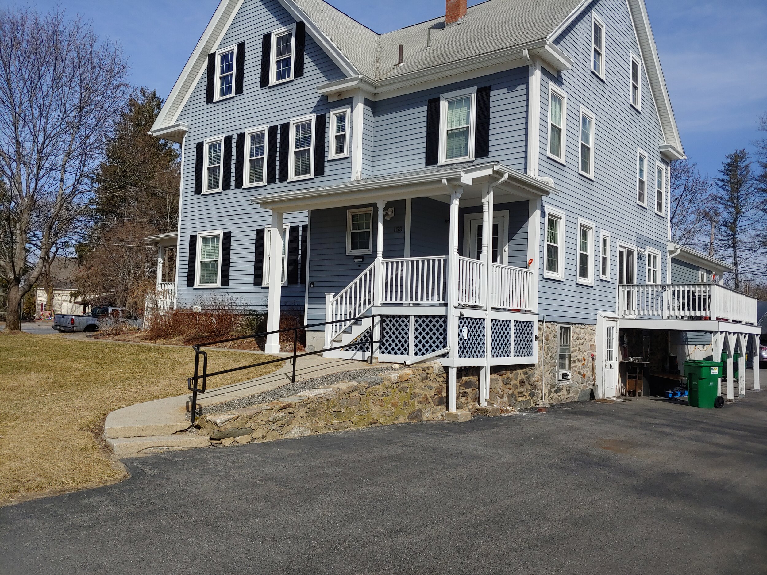 Front portico home addition with white railings and stairs in Hudson, MA