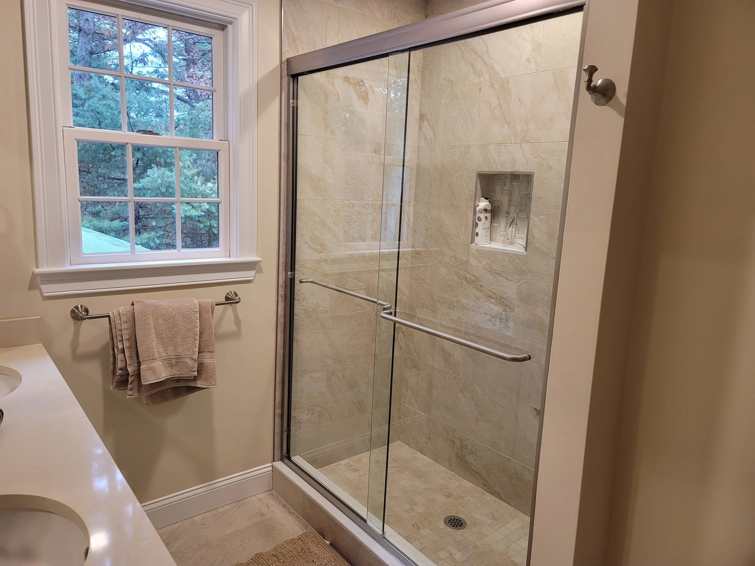 Family bathroom in Stow MA with tiled shower, glass door, and brushed nickel fixtures