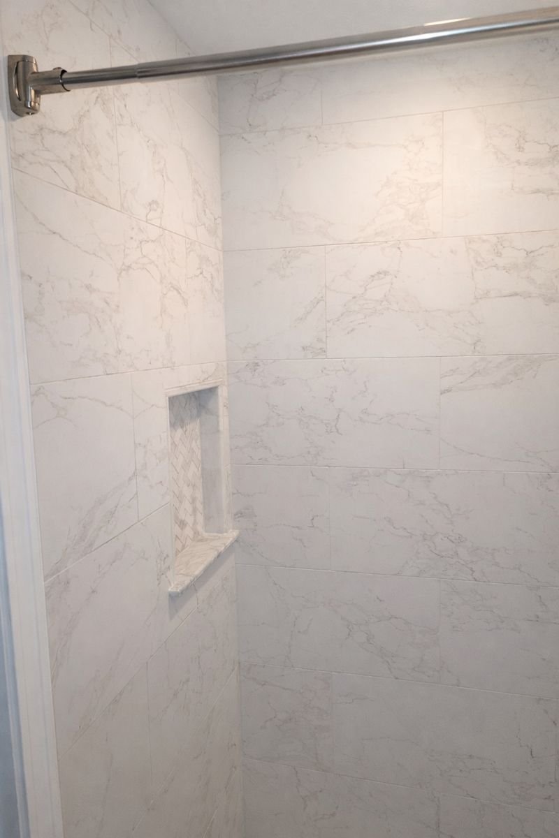 Walk-in shower floor with MSI Arabescato Venato herringbone tile and linear drain