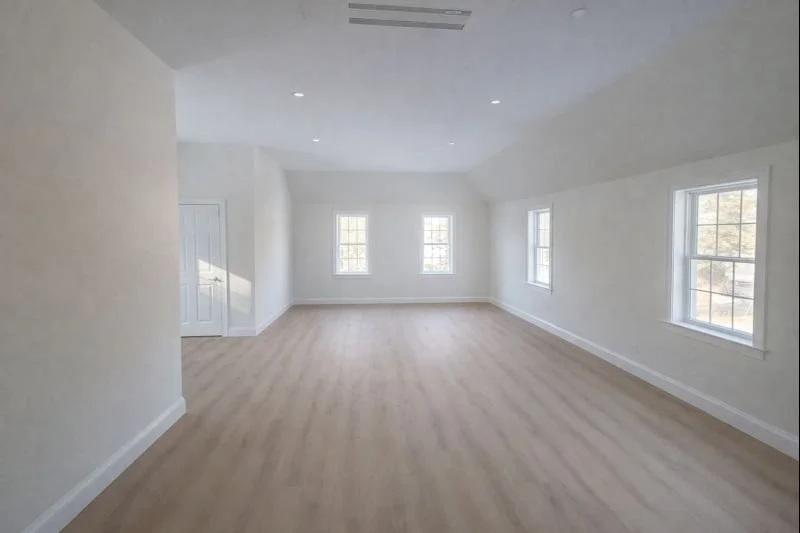 Wide interior view of a new home addition in Hopkinton, MA featuring an office space with five windows and recessed lighting