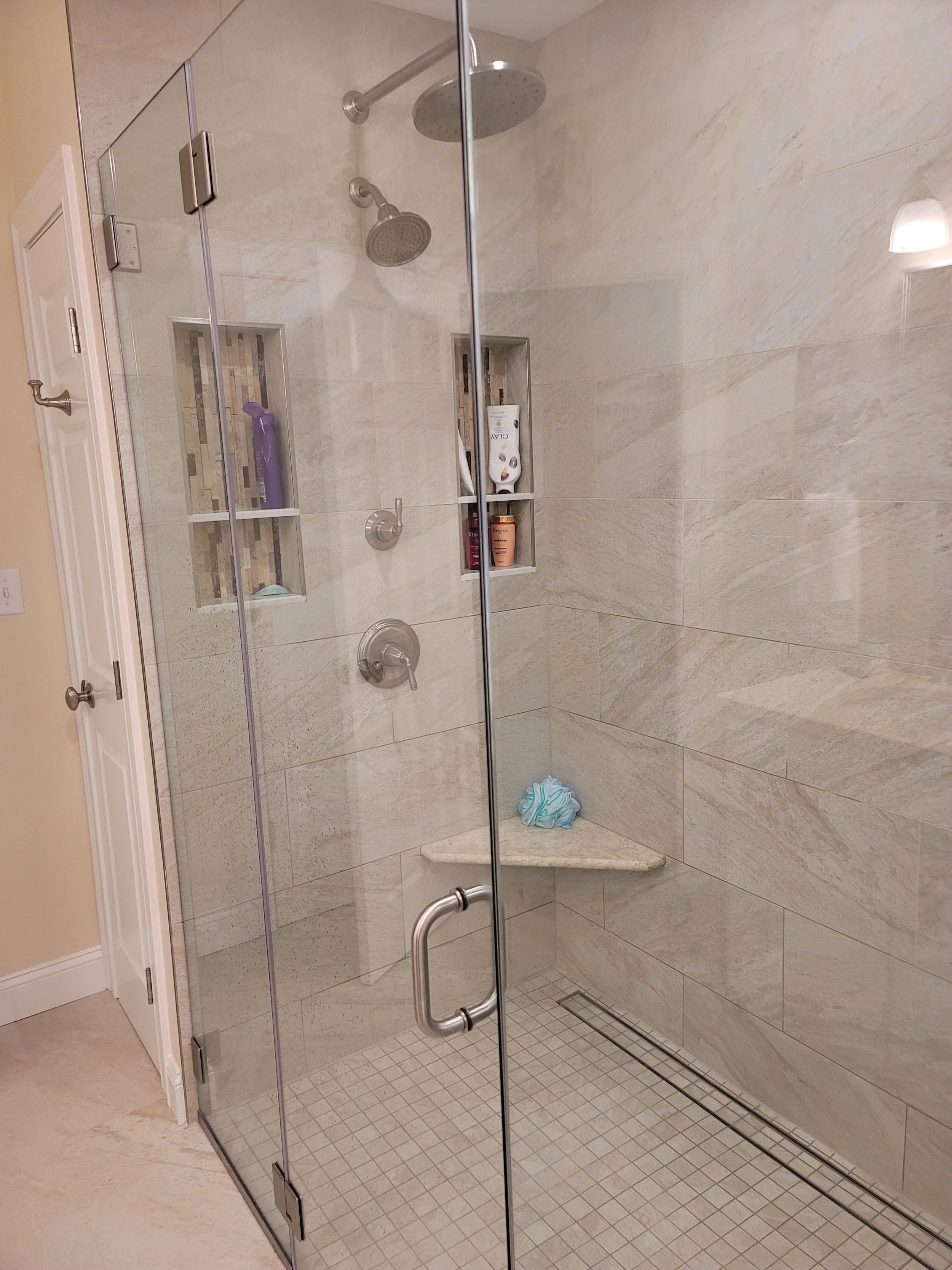 Custom tiled shower in a primary bathroom in Stow MA with glass enclosure and linear drain