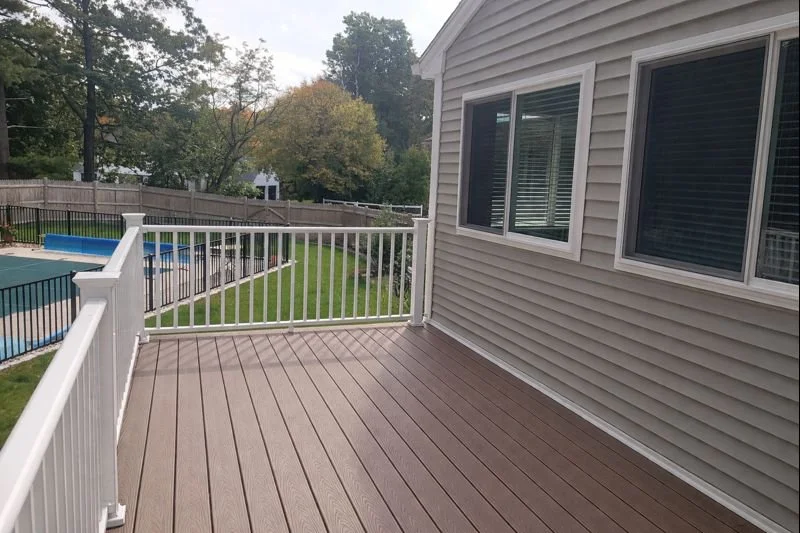 Elevated composite deck view alongside family room addition with railing