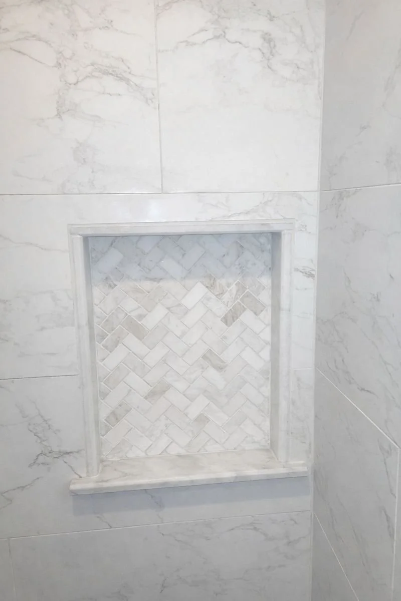 Shower niche with double-shelf design and herringbone tile inset