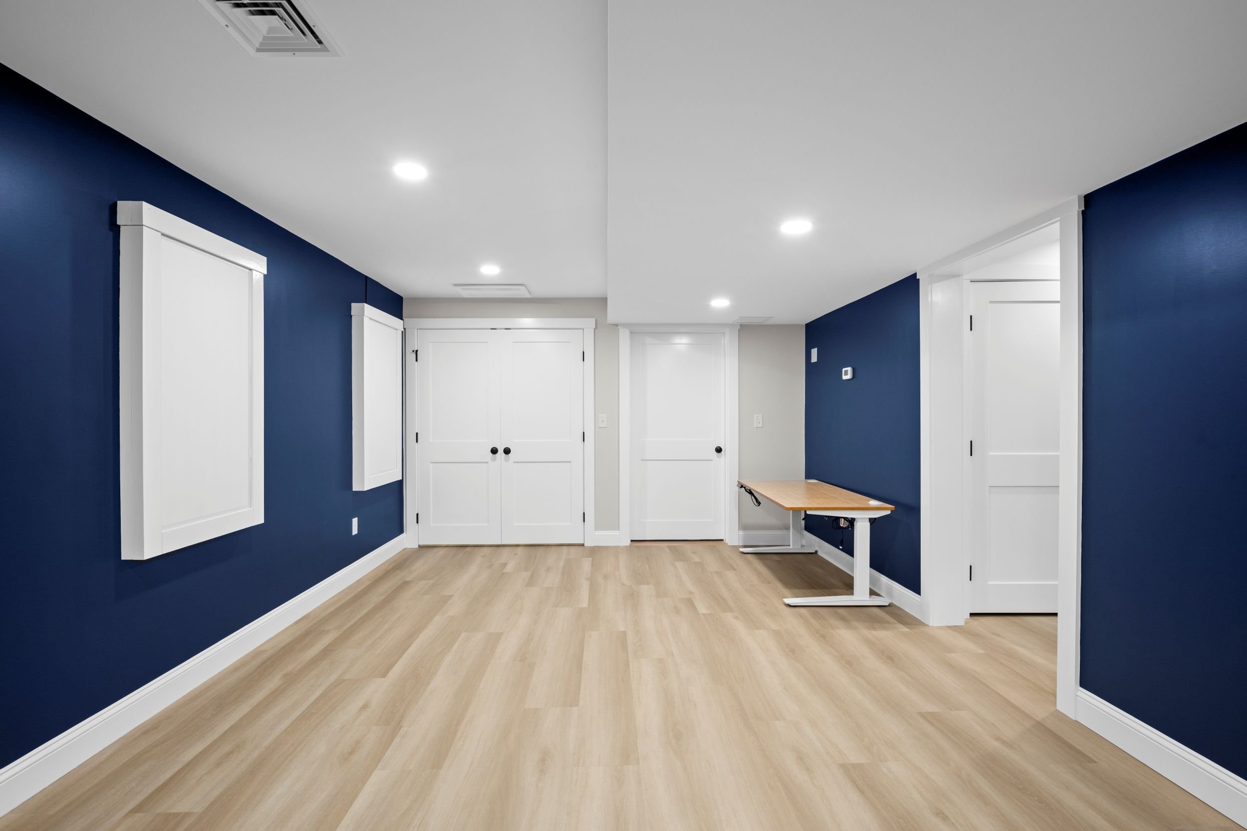 Finished basement family room in Boxborough, MA featuring a navy blue accent wall, recessed lighting, and an open-concept layout.