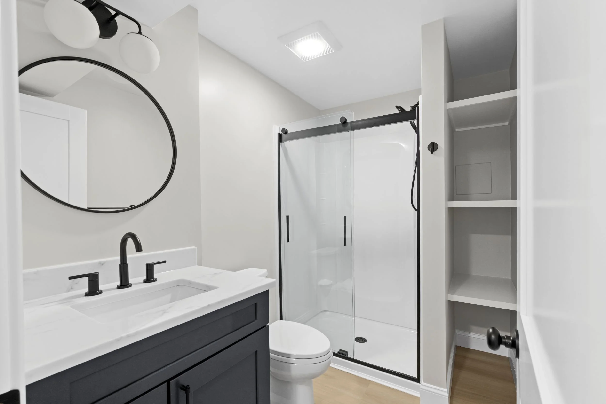Walk-in shower in a Boxborough, MA basement remodel, featuring large-format tile and a semi-frameless sliding glass door.