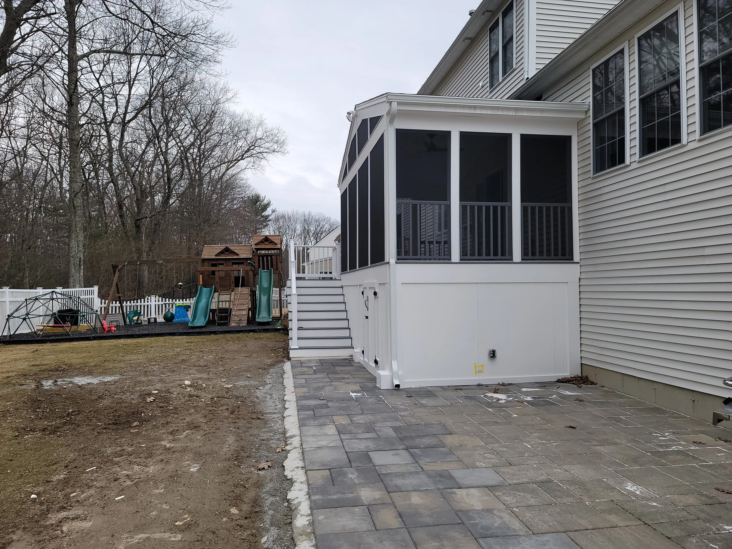 Three-season screen room in Ashland MA with paver patio extending along the side of the home