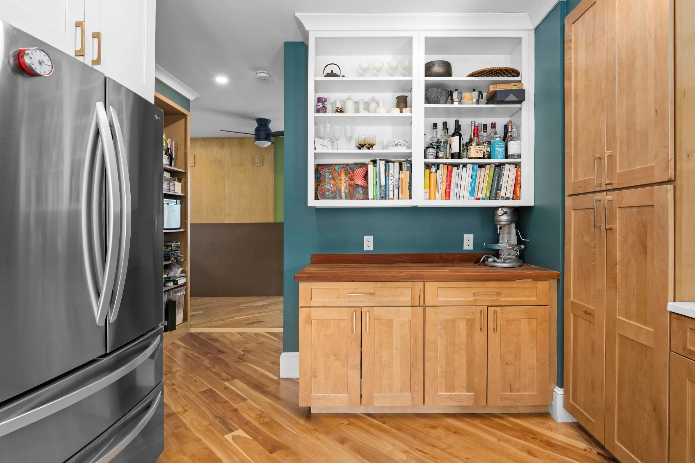 Baking station with open shelving, natural wood cabinetry, butcher block countertop, and teal accent walls in a Worcester, MA kitchen remodel.