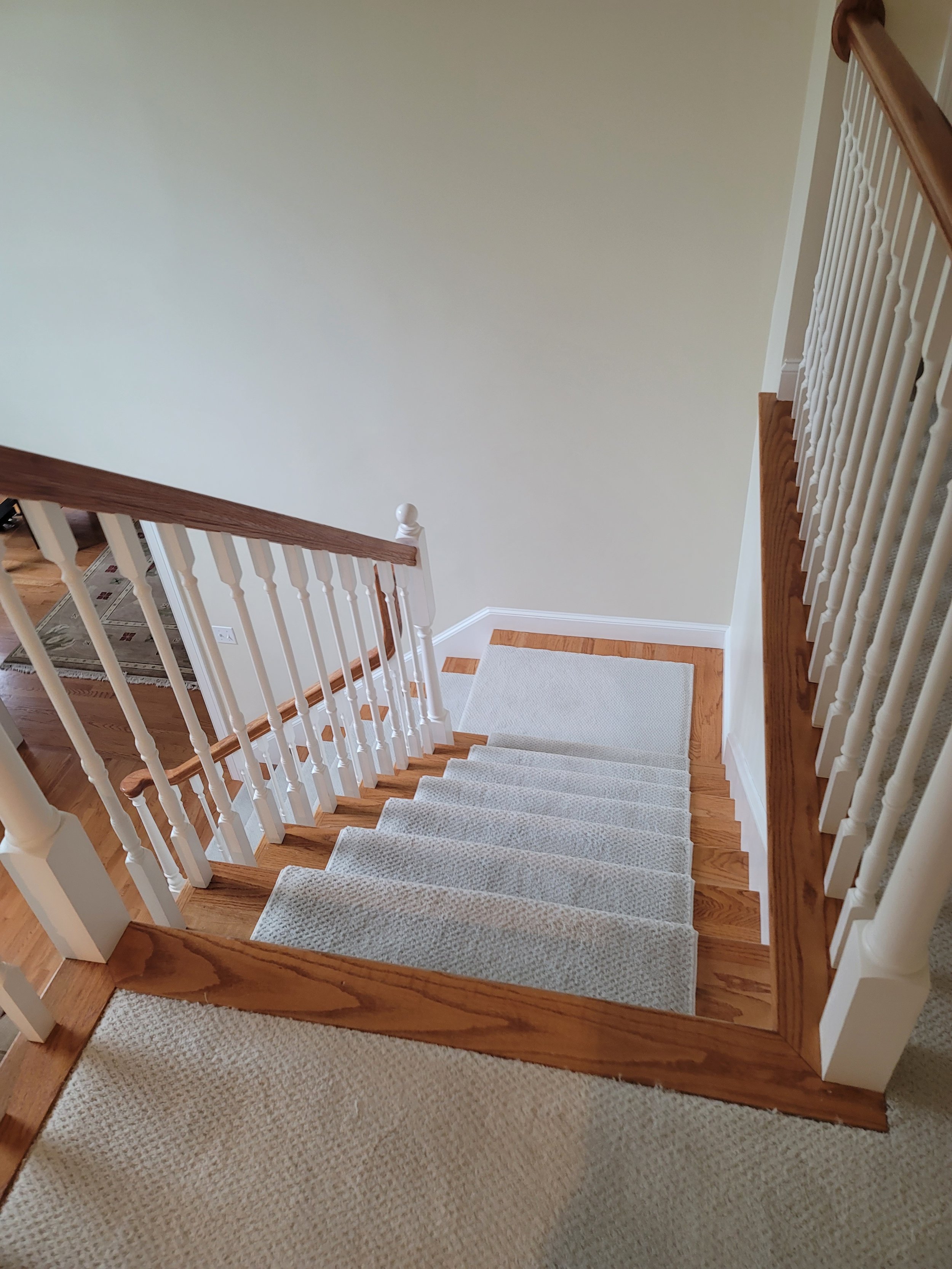 Carpeted staircase renovation with wood trim in a Stow MA home