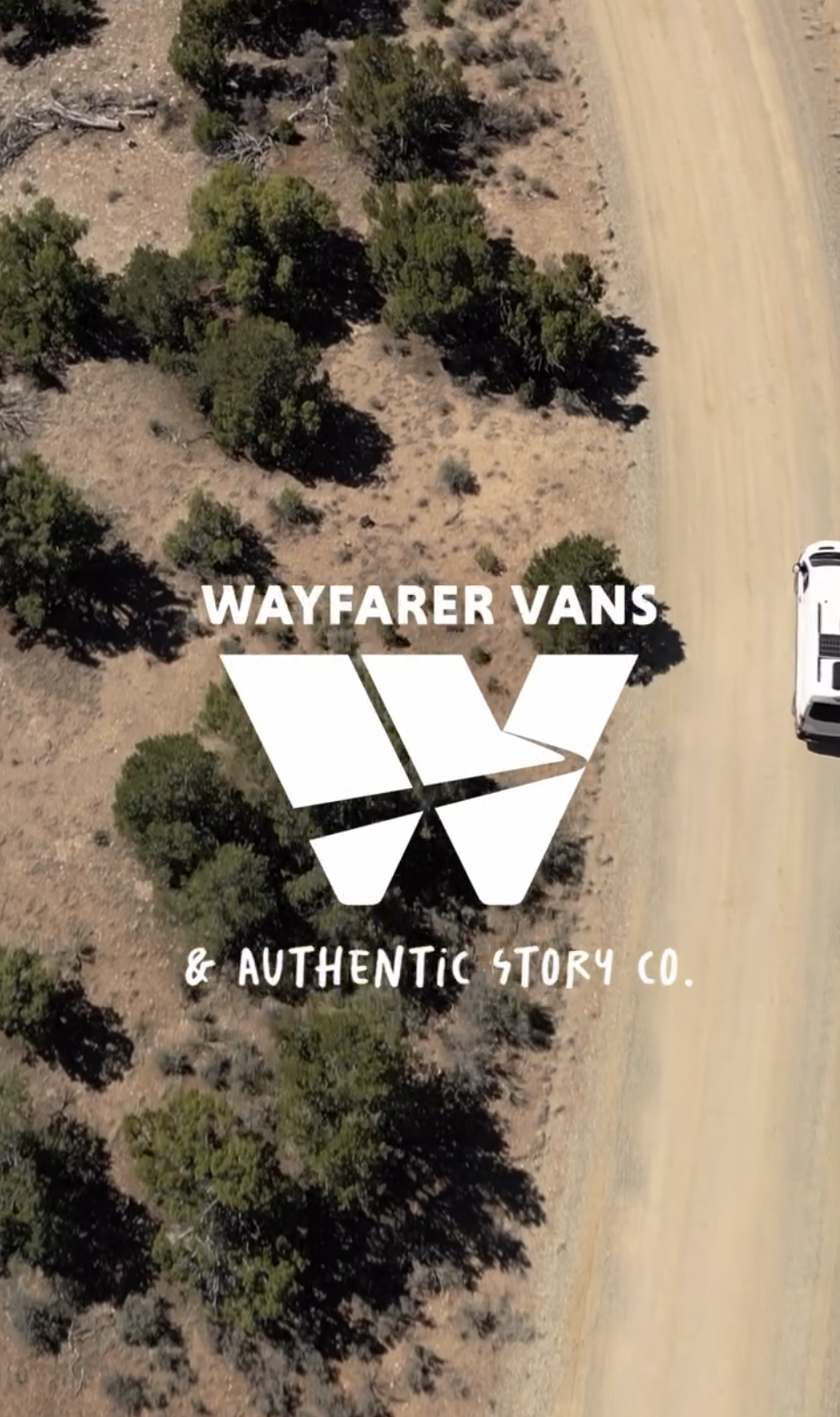 Wayfarer Vans and a big white "W", their logo, is in the middle of the photo. Below that it says Authentic Story Co. It's an aerial shot of a desert landscape and part of a white van on a dirt road.