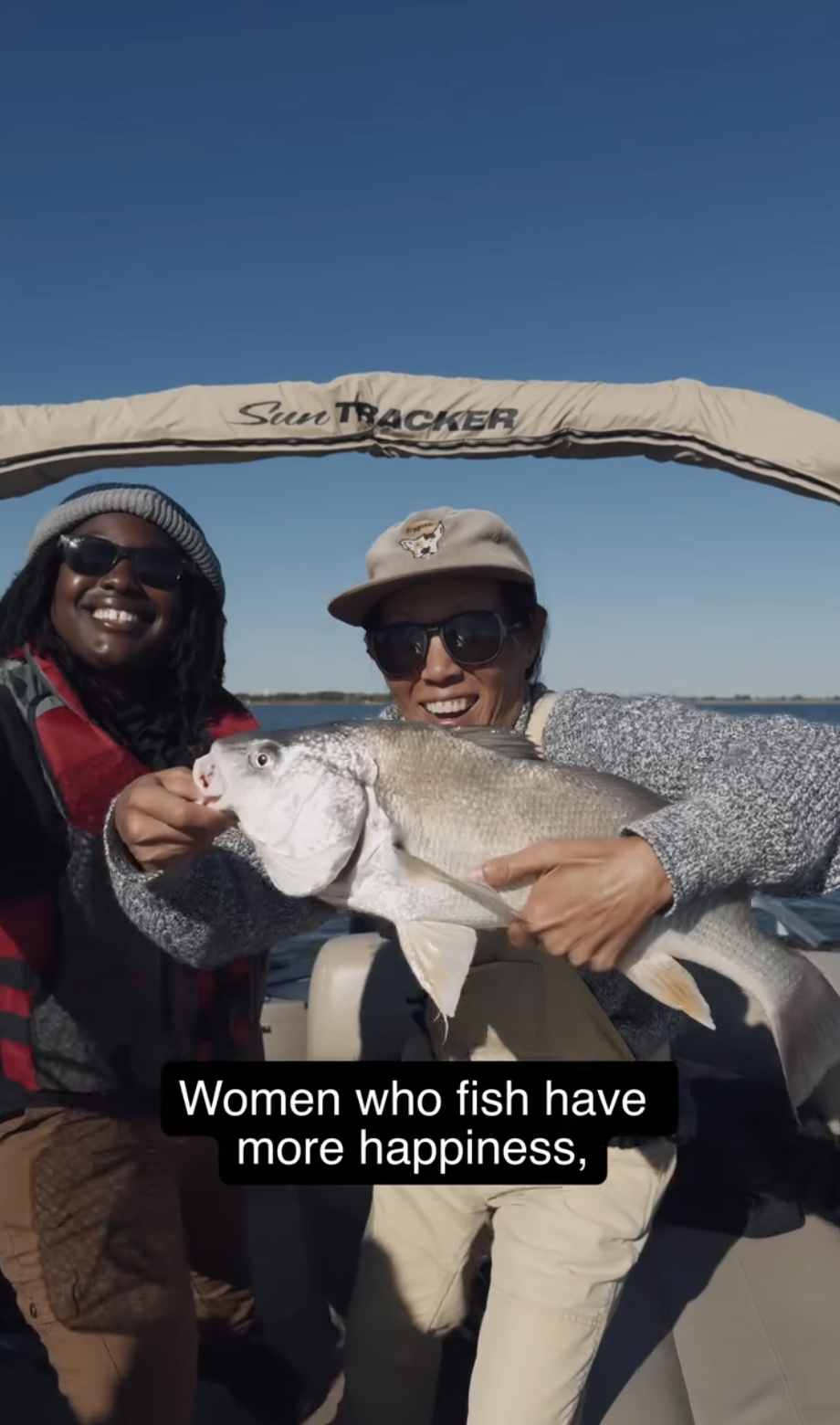 Erin McGrady is holding a large fish. She's on a boat with another woman. They are both smiling. The caption below says "Women Who Fish Have More Happiness"